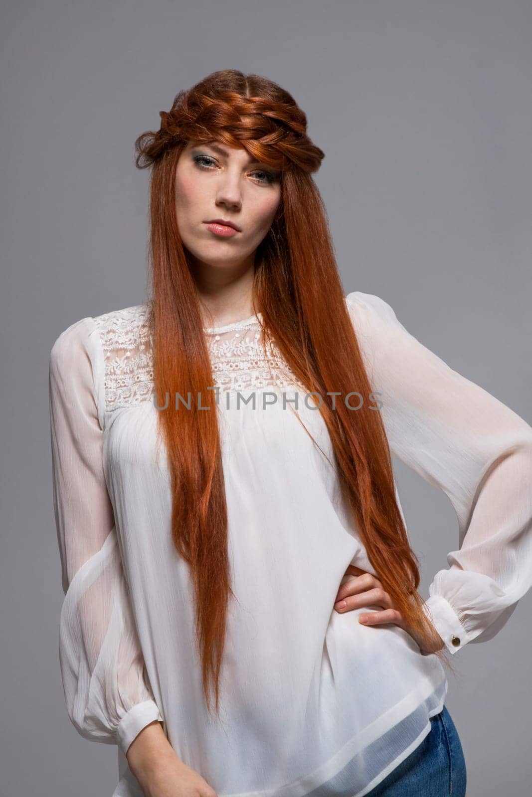 Young attractive female girl with long red hair in portrait against grey background