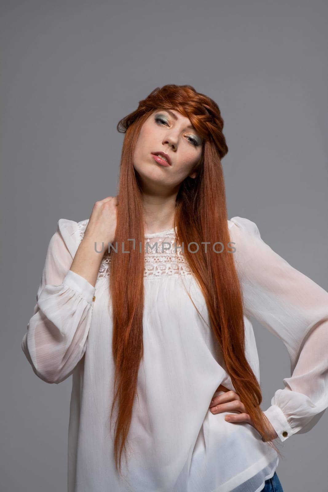 Young attractive female girl with long red hair in portrait against grey background