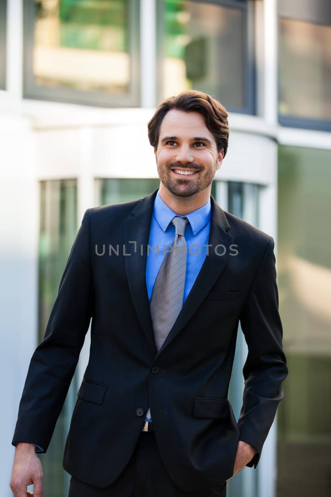 Young trendy businessman in front of a business building successfully with beard and dark hair