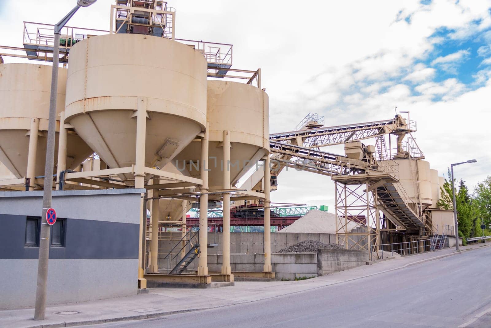 Large storage containers in a gravel plant for outdoor concrete production under a blue sky