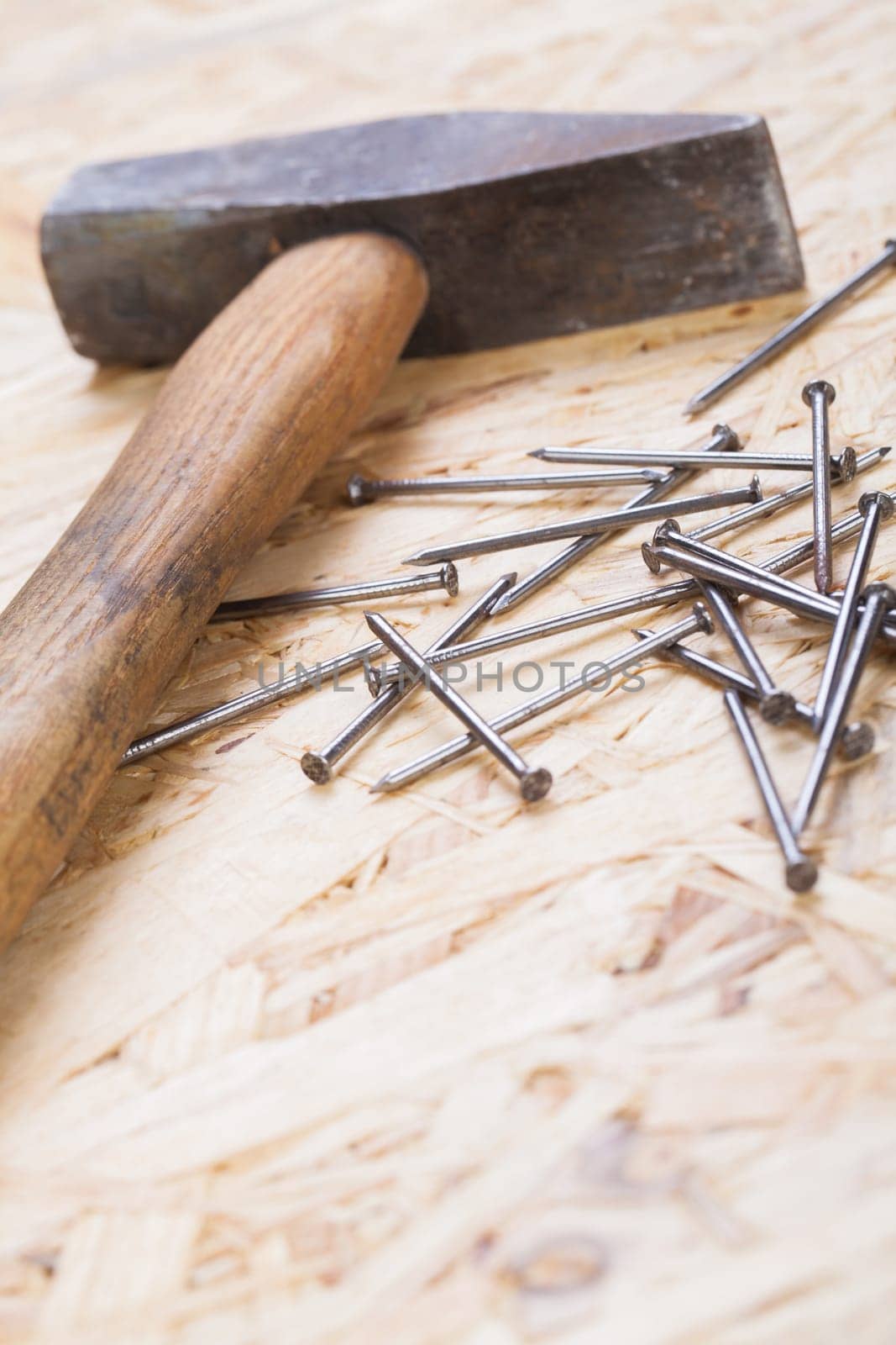 Hammer with nails on a wooden board in a workshop of a do-it-yourselfer