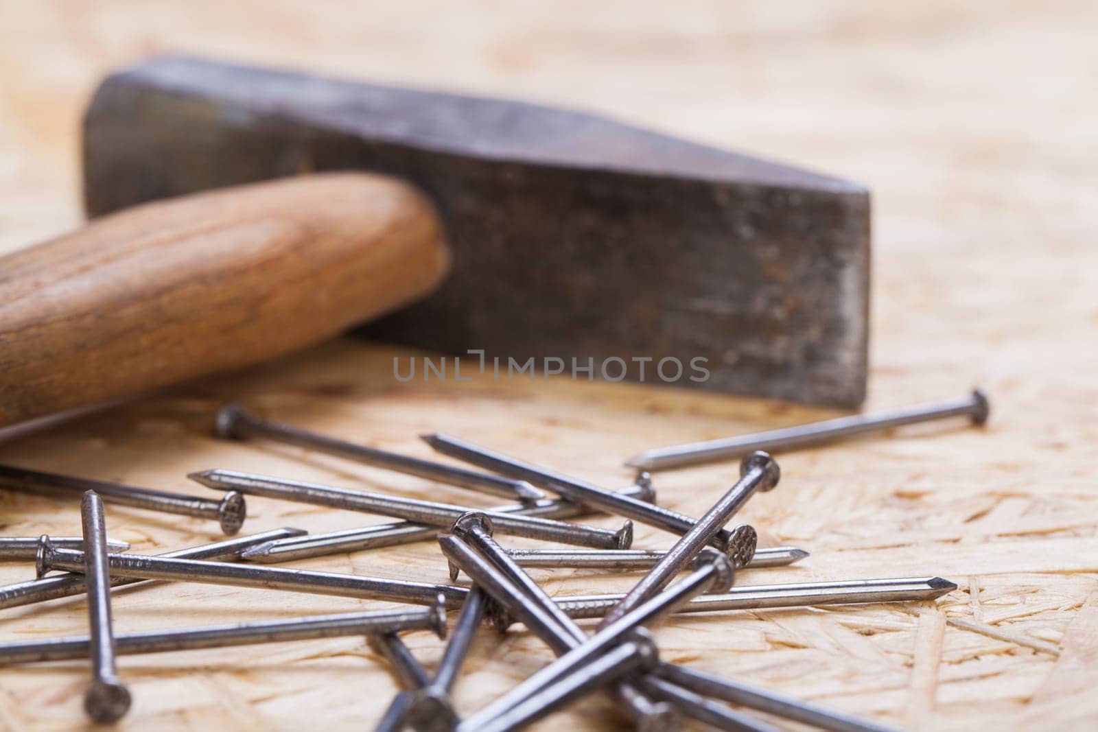 Hammer with nails on a wooden board in a workshop of a do-it-yourselfer