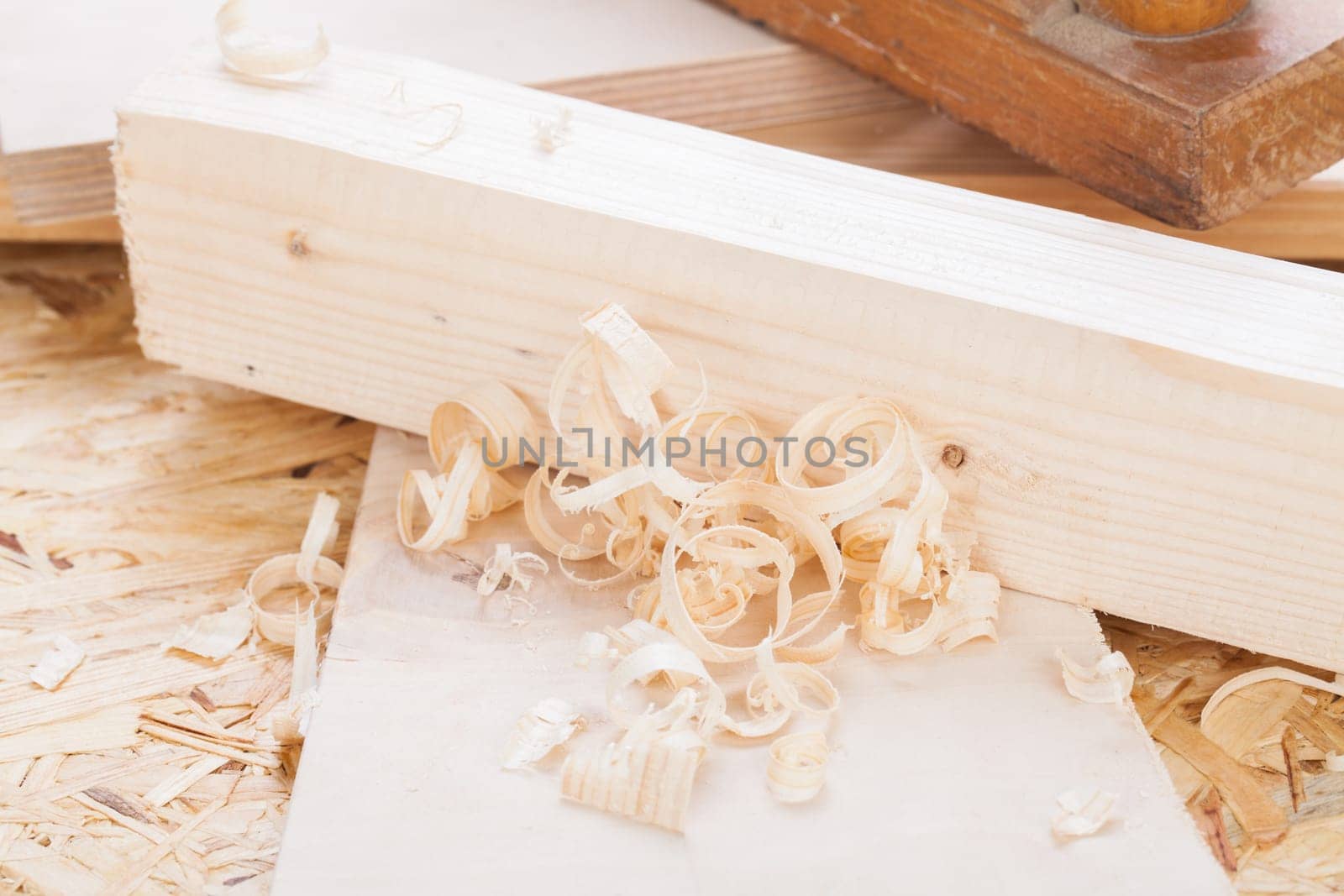 Planing with wood chips in a carpentry shop during woodworking in close-up detail