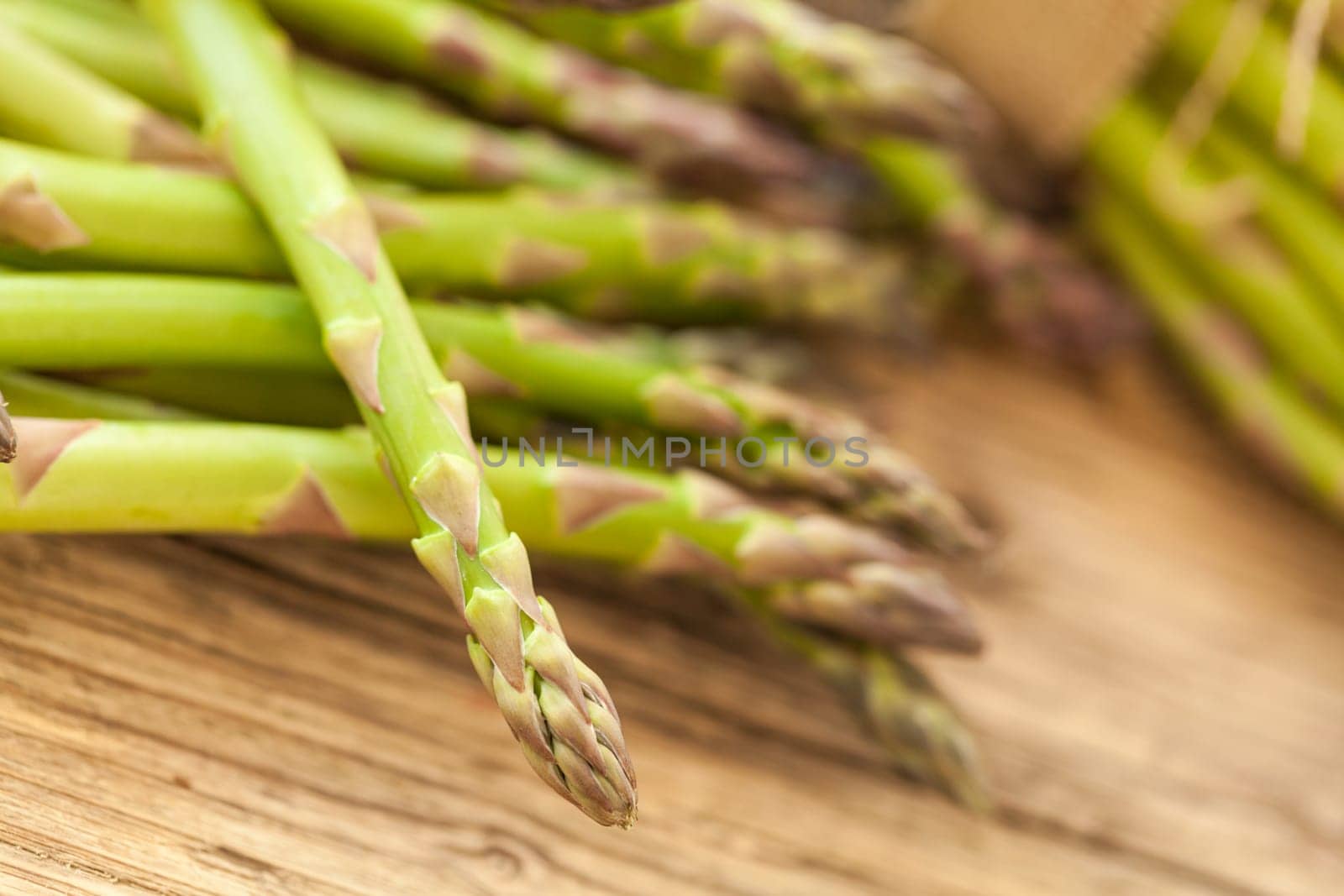 Fresh healthy green asparagus as a close-up on a wooden table in sunlight