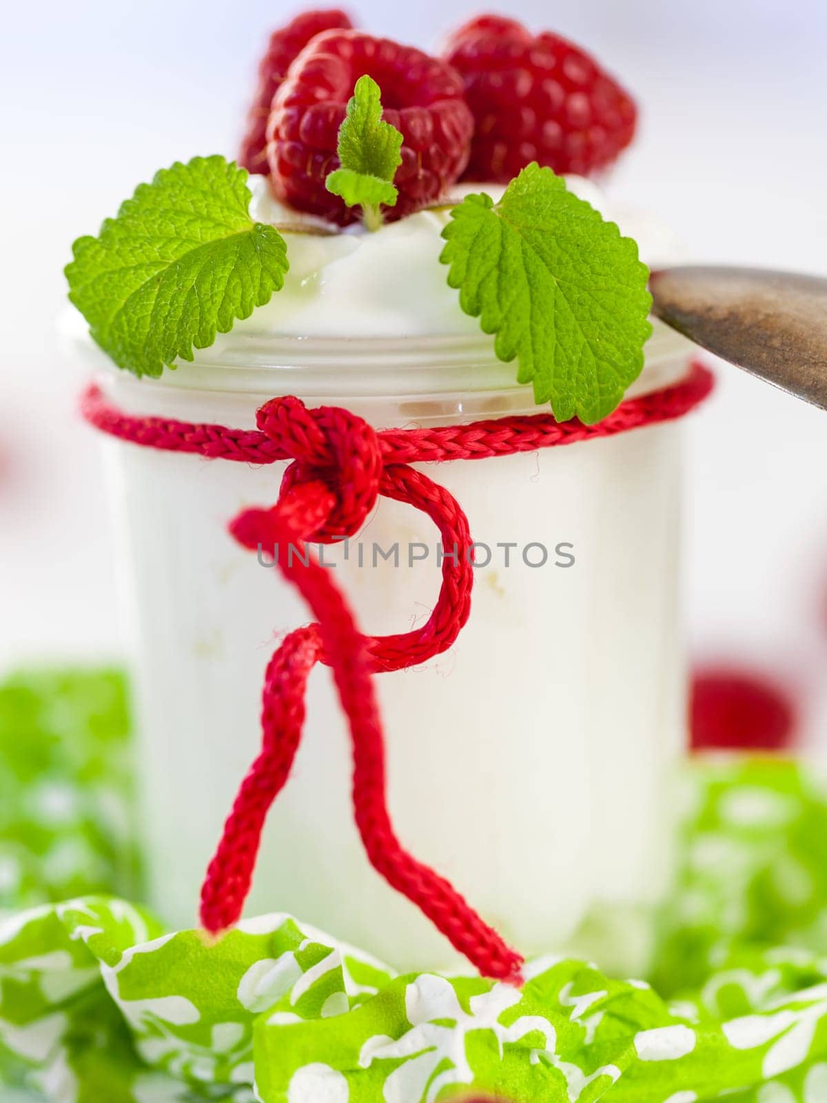 Fresh yoghurt with raspberries in a glass insulated on a white background