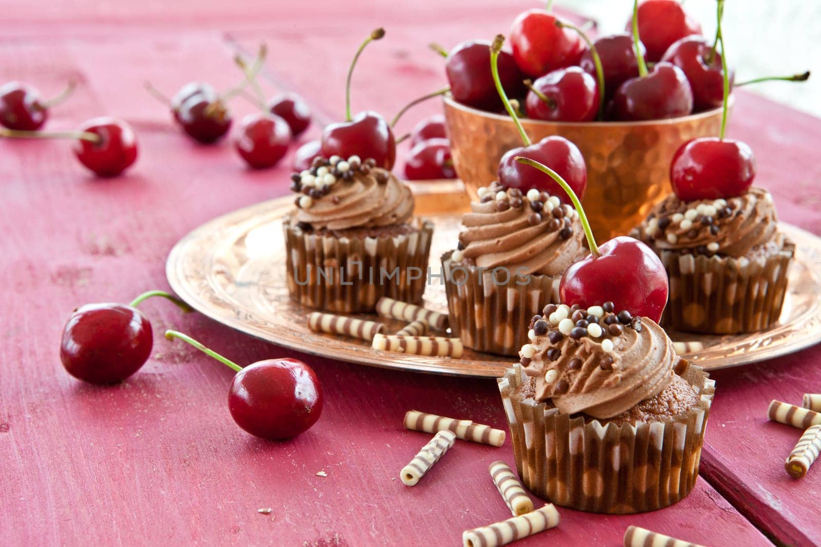 Chocolate cupcakes with buttercream and fresh cherries