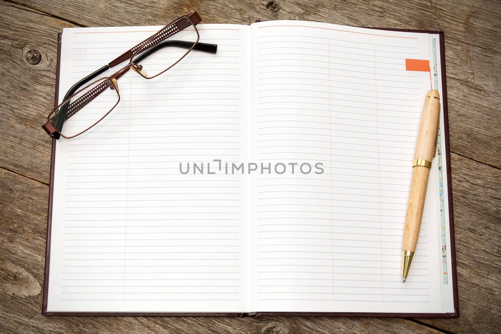 Open notebook with pen and glasses on a wooden background
