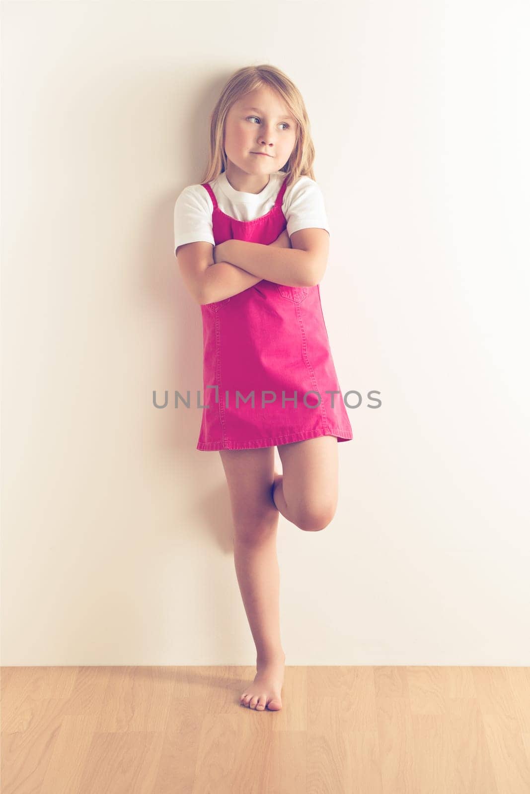 Little girl posing in front of a wall. Studio shot.