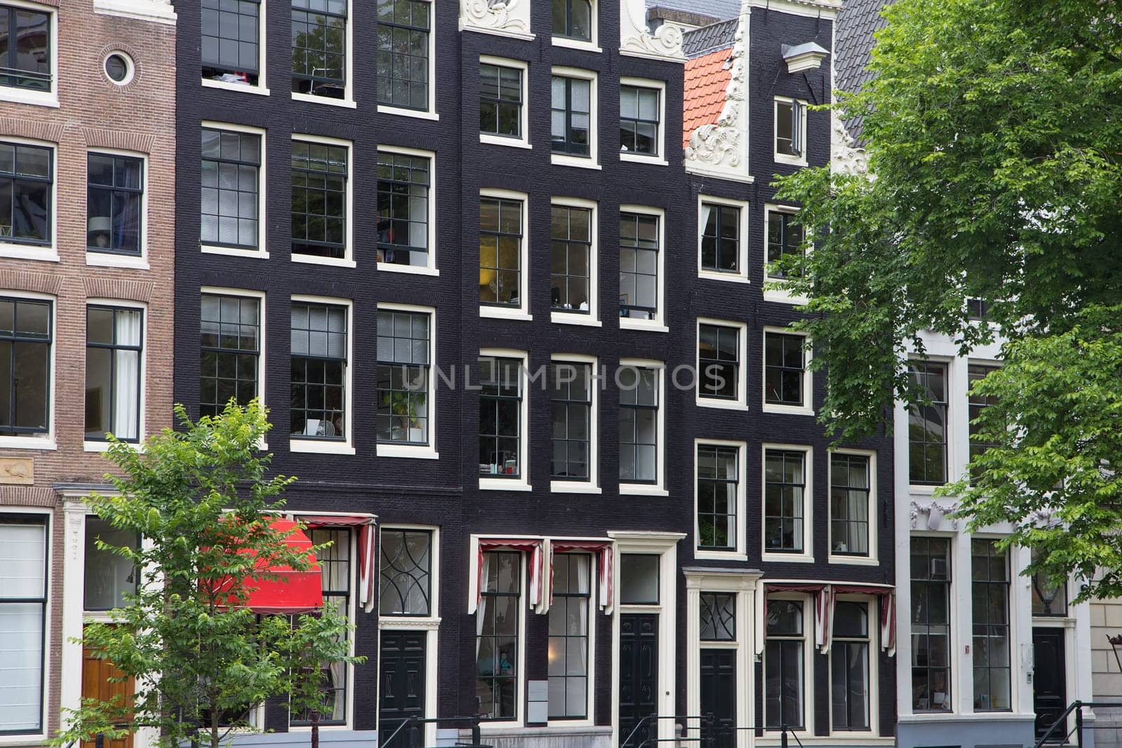 Close up view of the narrow houses along the canals in Amsterdam. (The Netherlands). All potential trademarks are removed.