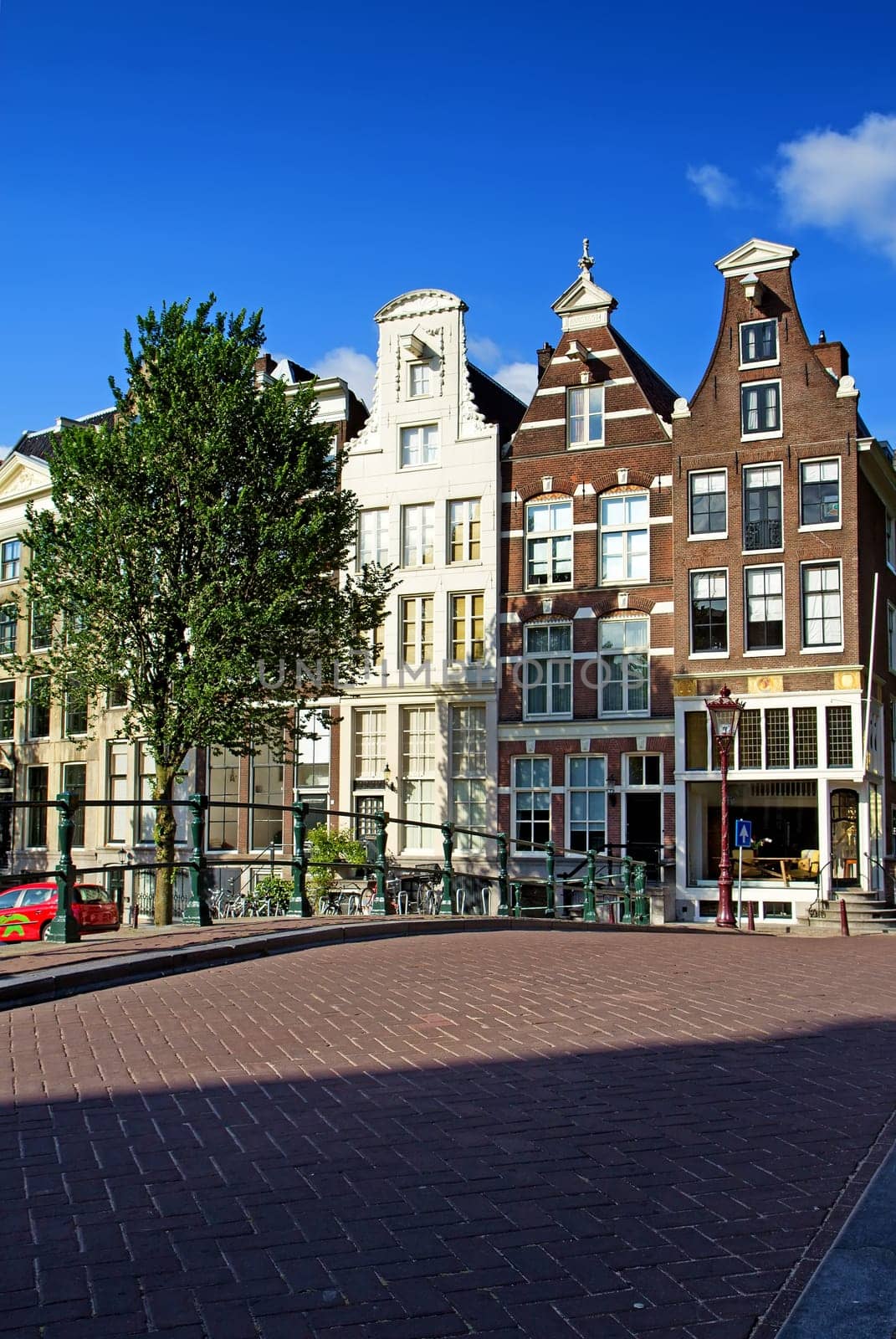 Bridge and the narrow houses along the canals in Amsterdam. (The Netherlands). All potential trademarks are removed.