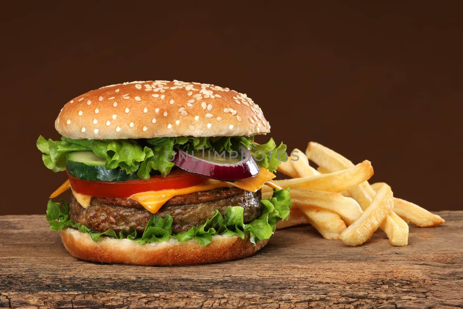 Tasty hamburger and french frites on wood background.