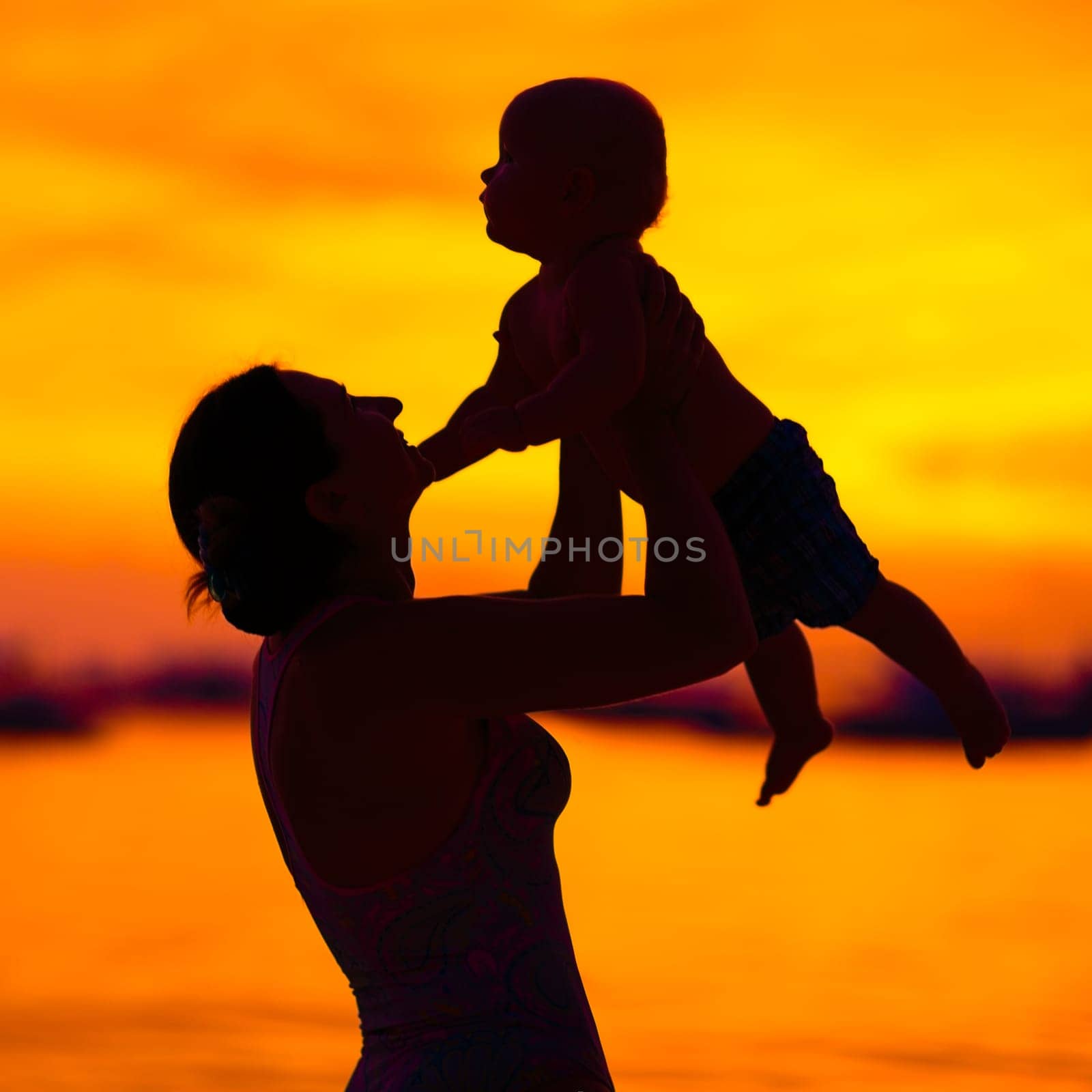 Silhouette of mother and baby at sunset
