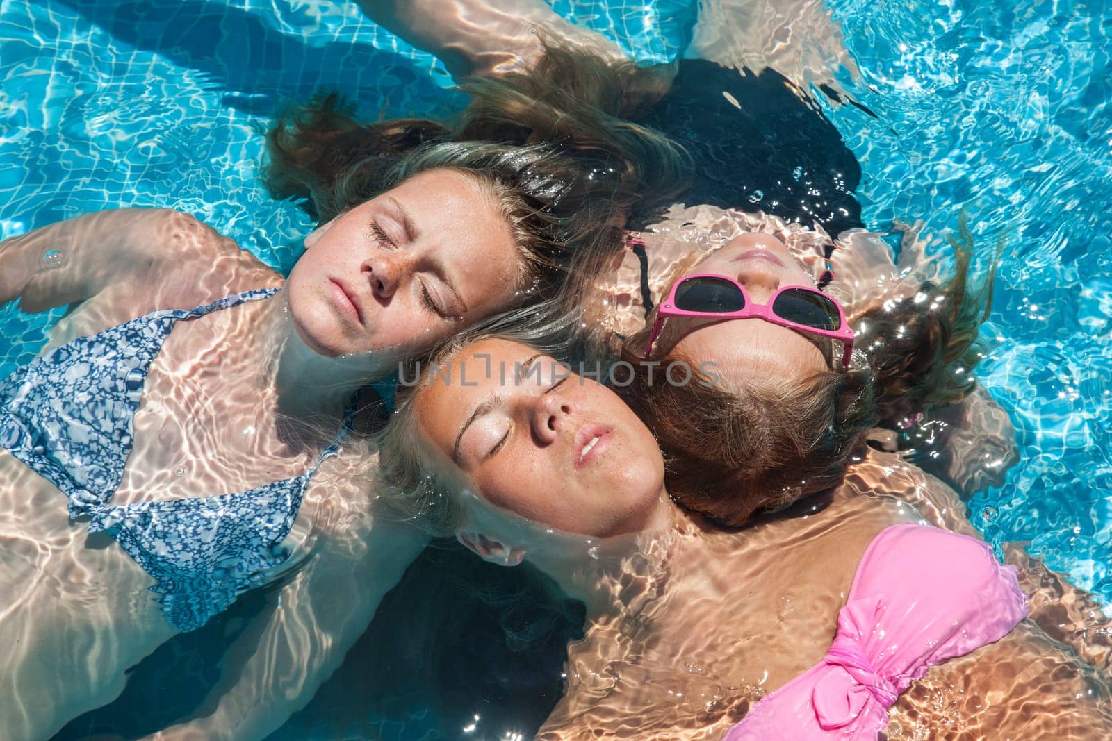 three girls relaxing in a pool in the summertime