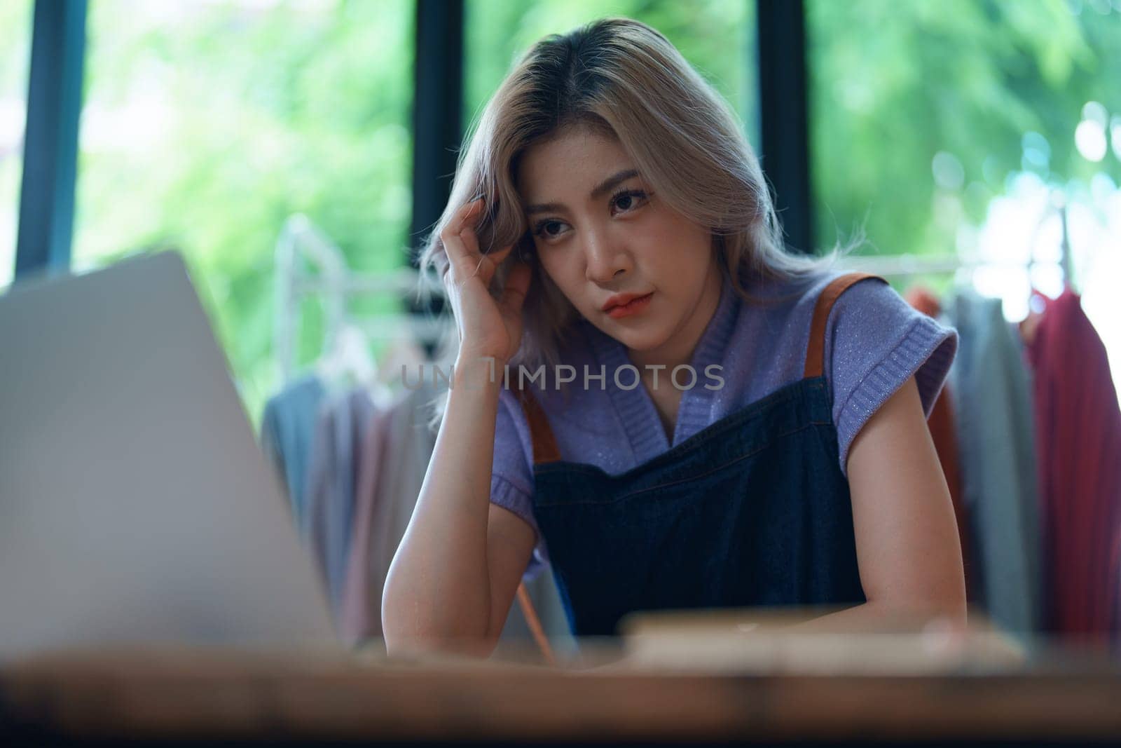 Starting small business entrepreneur of independent Asian woman showing her face worried about the sales of her business not reaching the target set. SME concepts by Manastrong