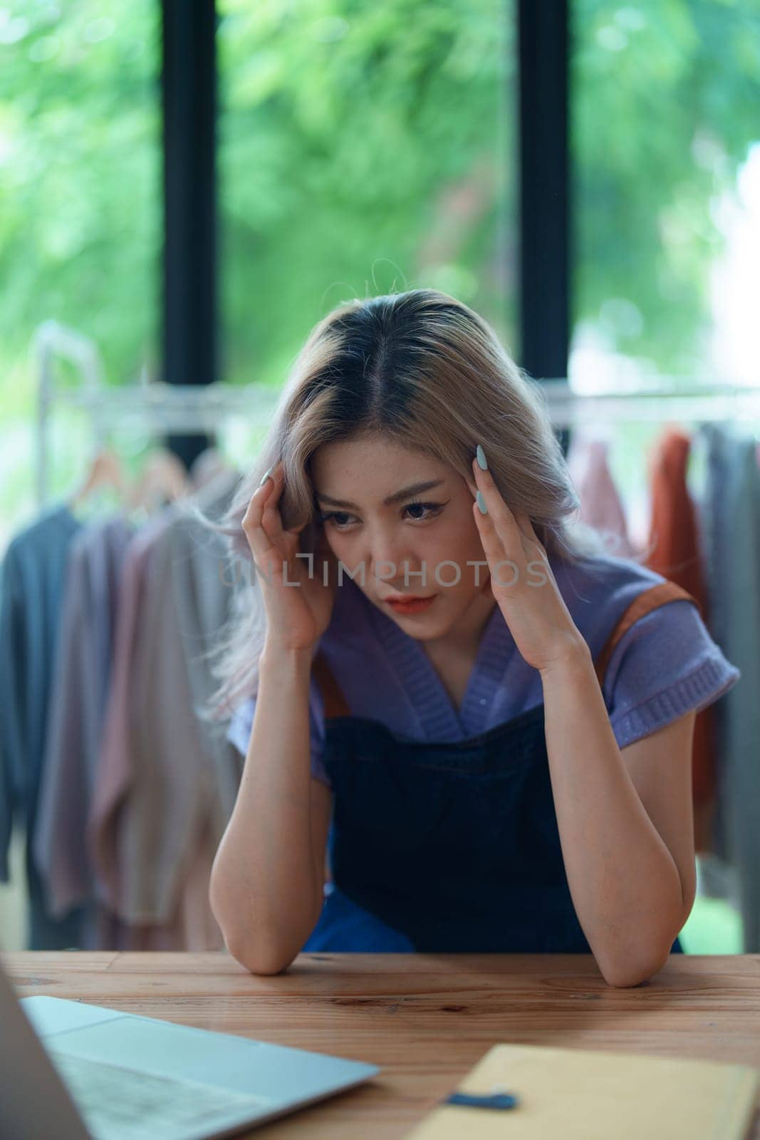 Starting small business entrepreneur of independent Asian woman showing her face worried about the sales of her business not reaching the target set. SME concepts.