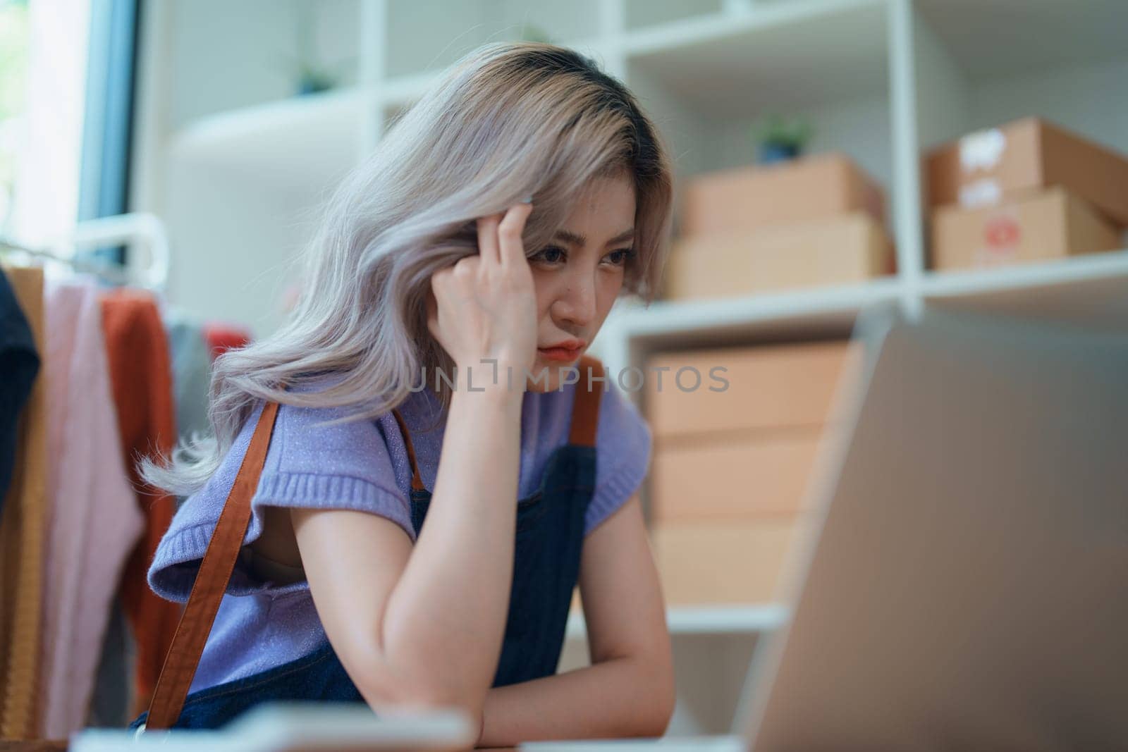 Starting small business entrepreneur of independent Asian woman showing her face worried about the sales of her business not reaching the target set. SME concepts.