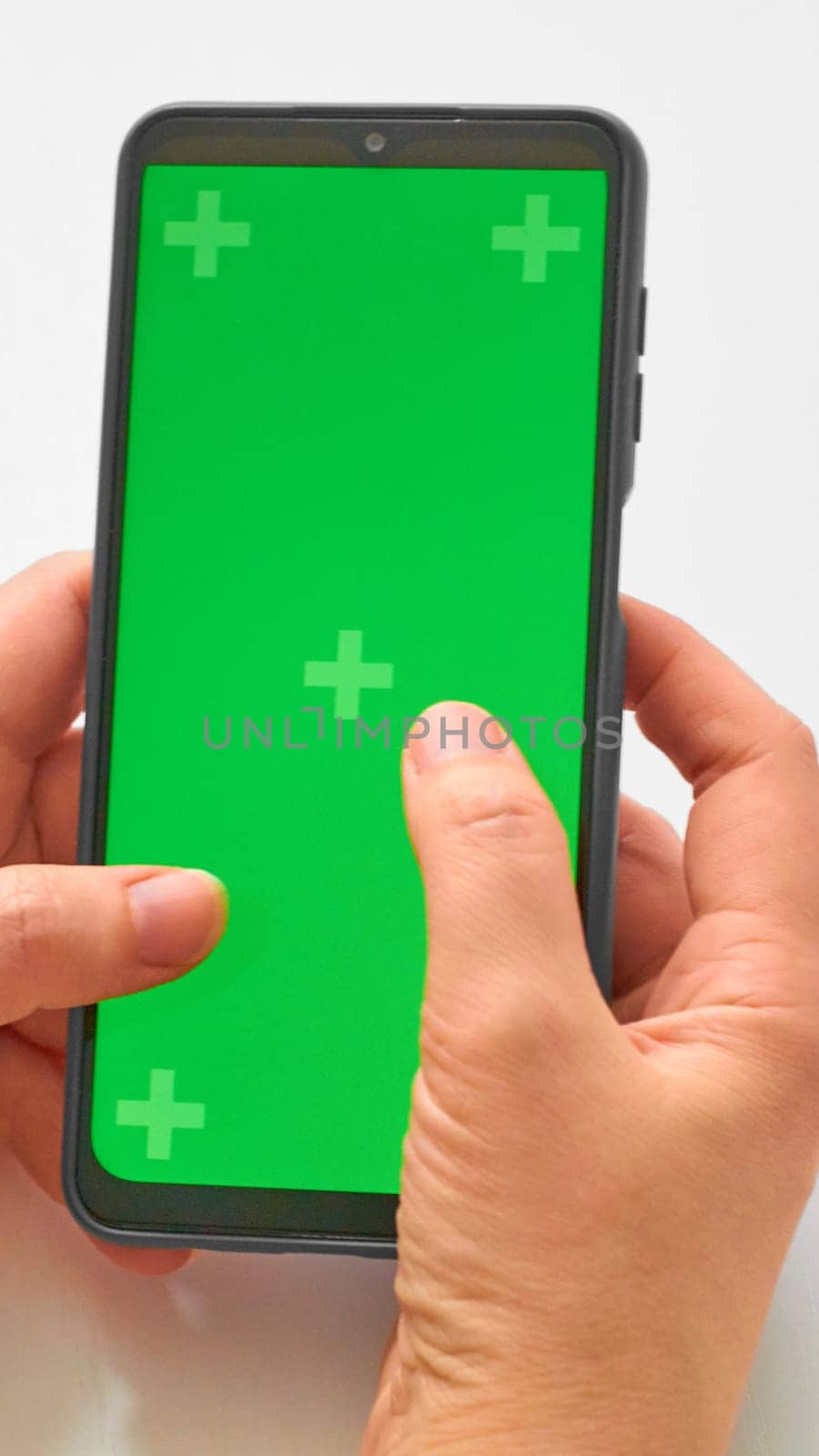 Elderly woman hands holding smartphone with green screen. The chromakey. Green screen