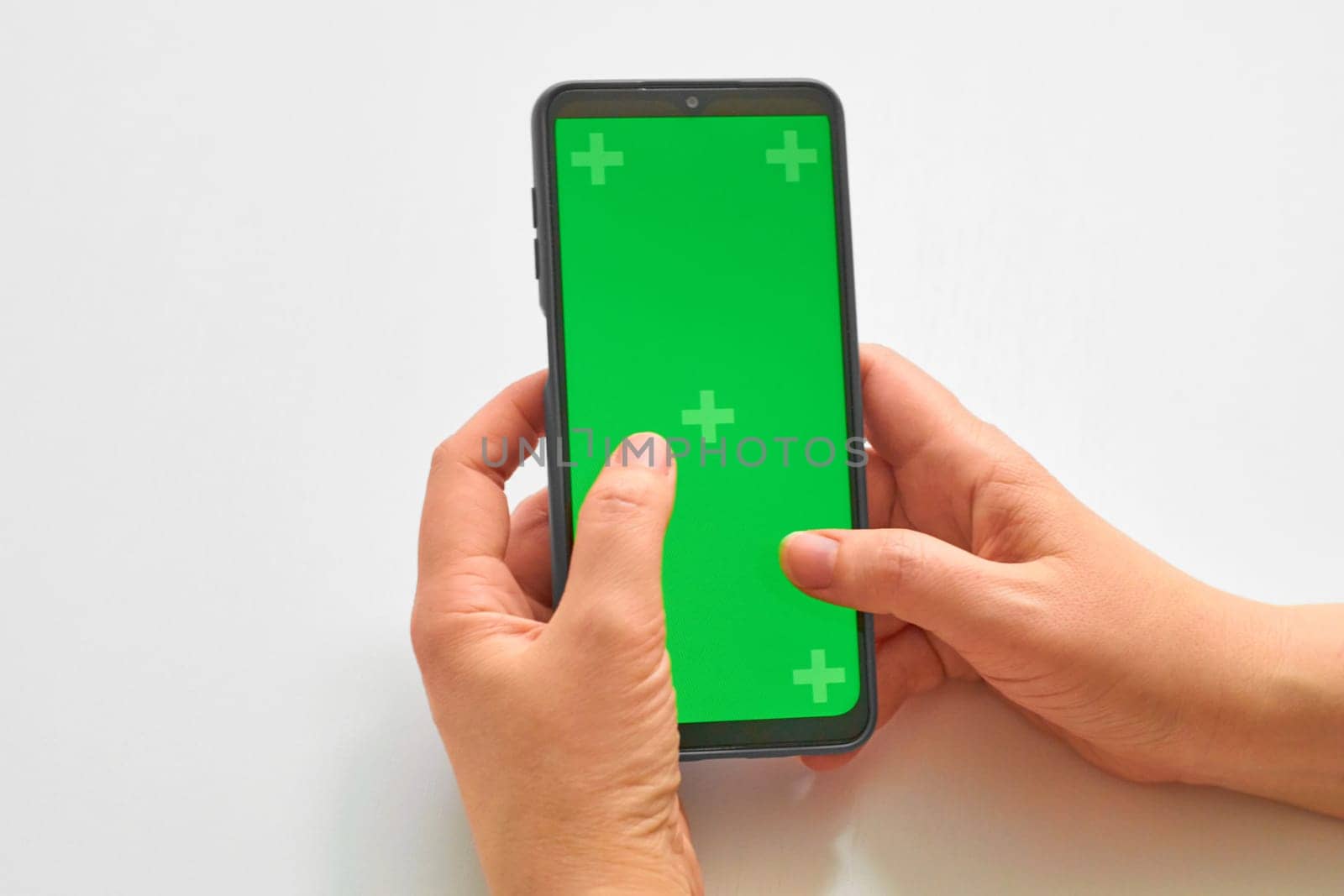 Elderly woman hands holding smartphone with green screen. The chromakey. Green screen