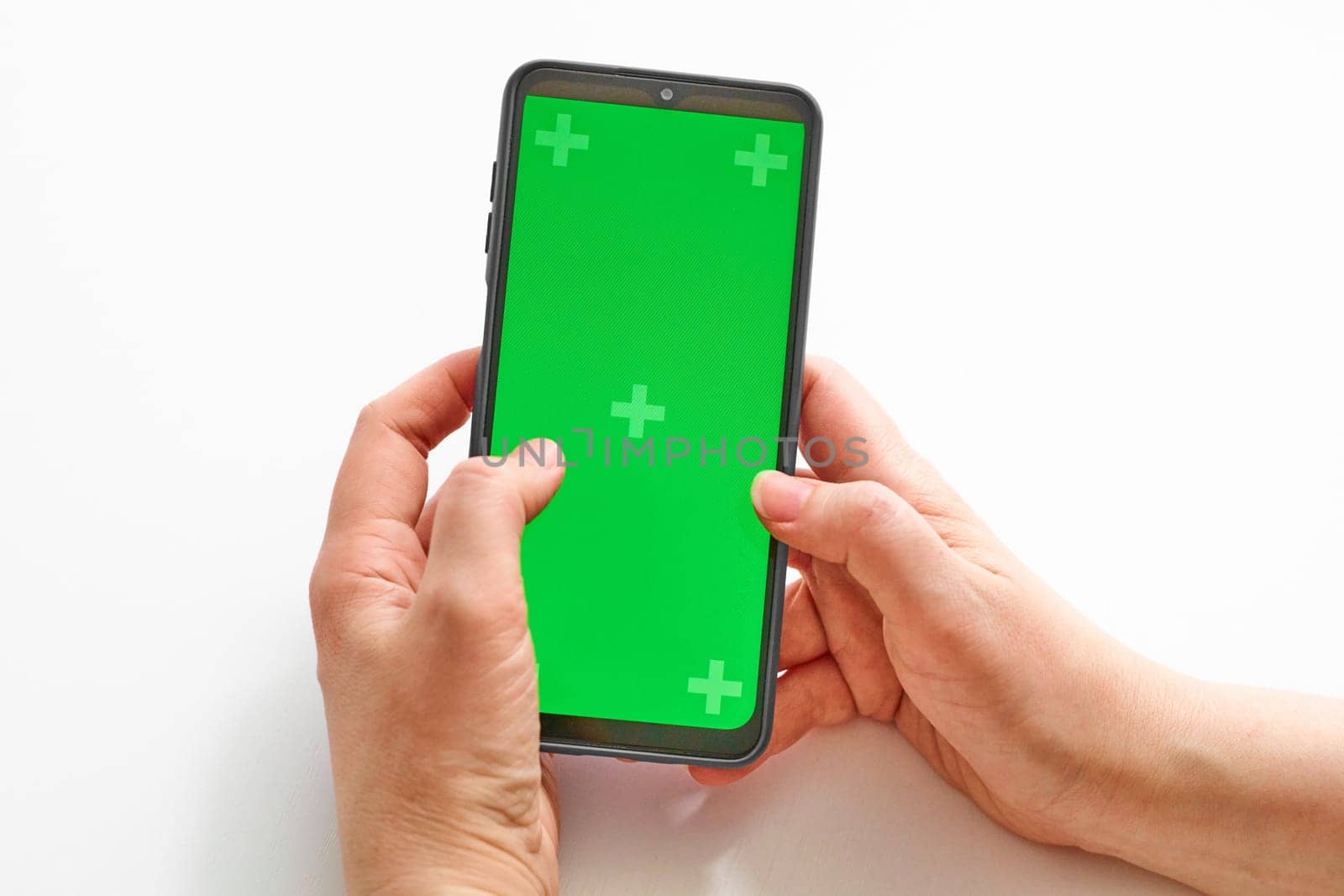 Elderly woman hands holding smartphone with green screen. The chromakey. Green screen