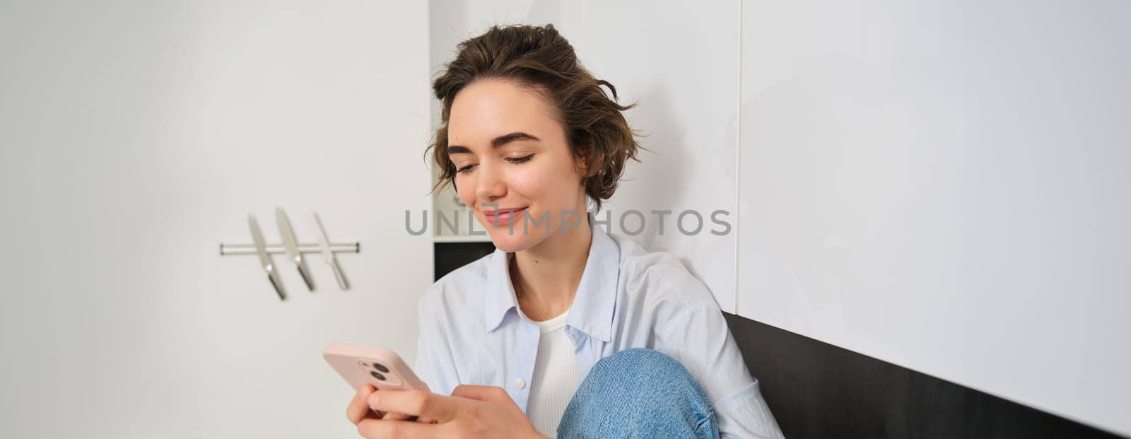 Portrait of woman sitting at home with mobile phone, online shopping on smartphone app, spending time indoors.