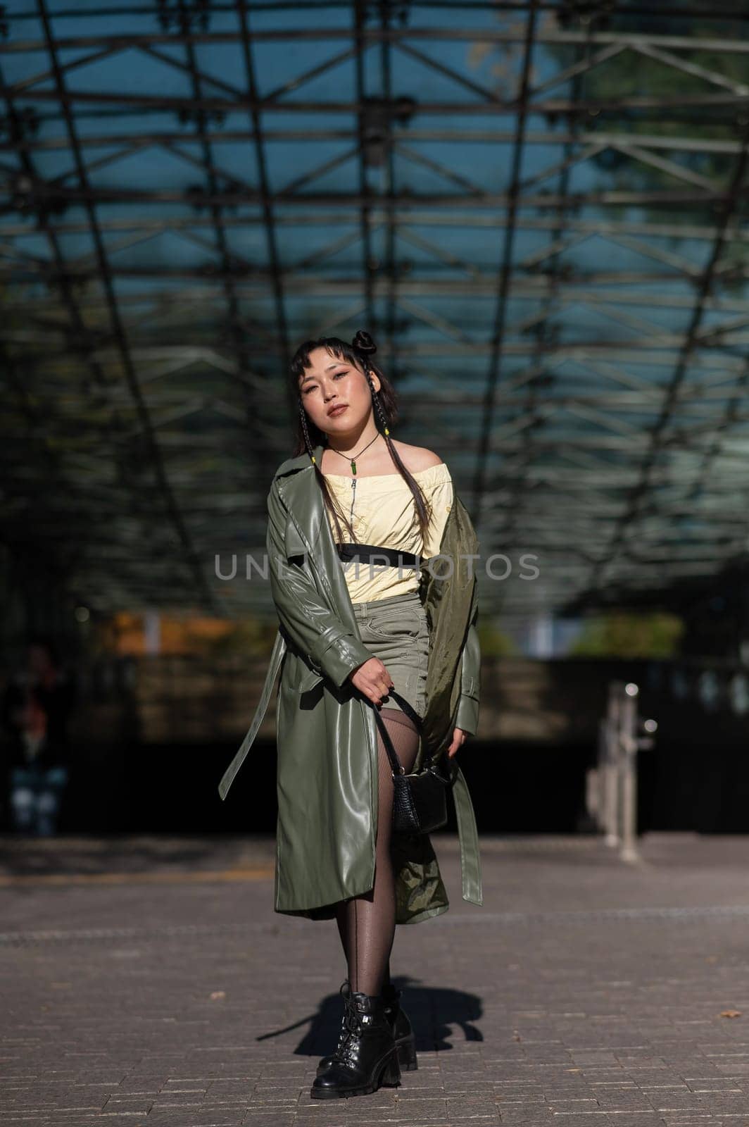 A beautiful Asian woman in shorts and a green leather coat comes out of the subway