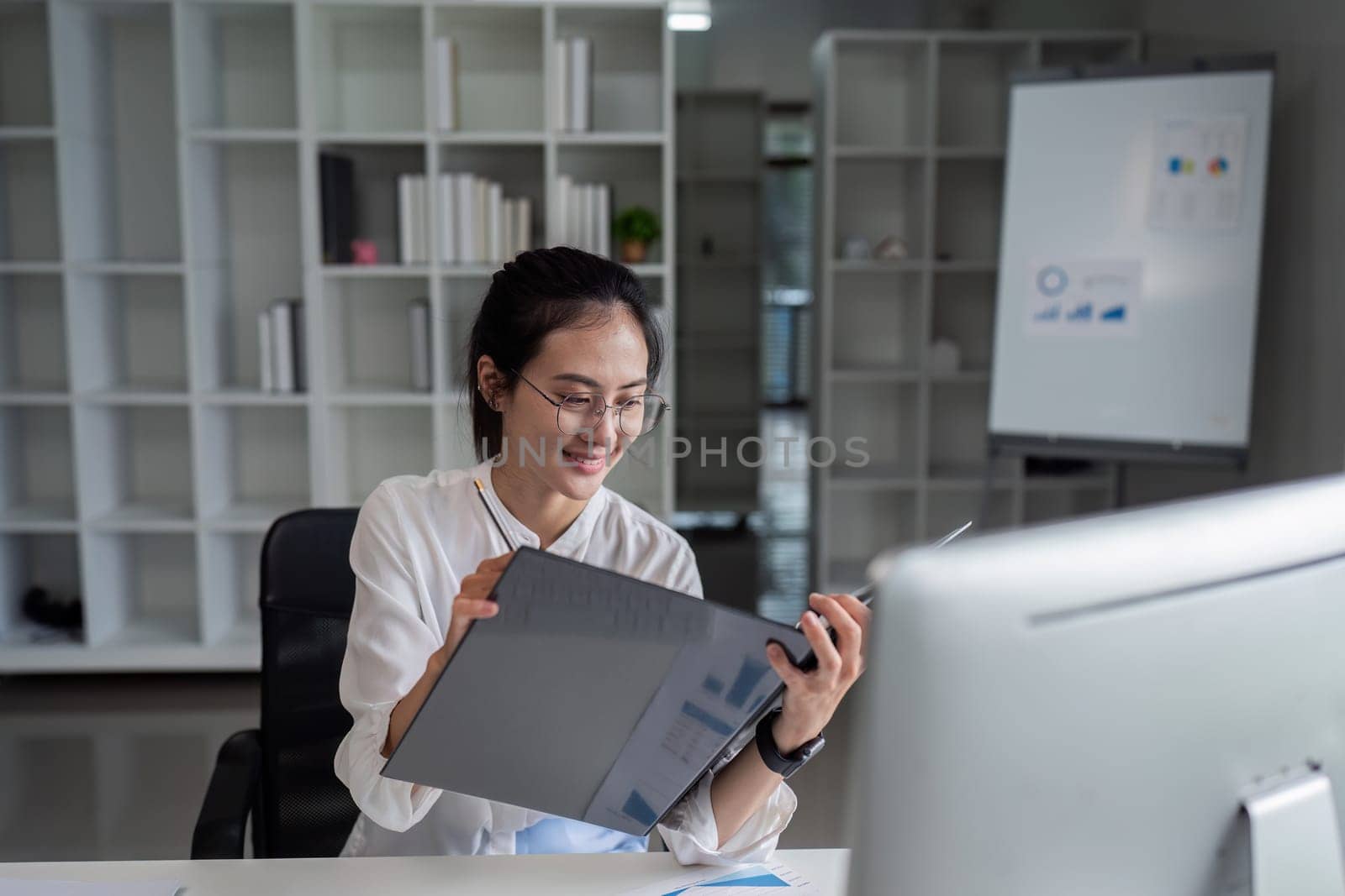 businesswoman accountant using file and computer for matching financial data saving in office room by itchaznong