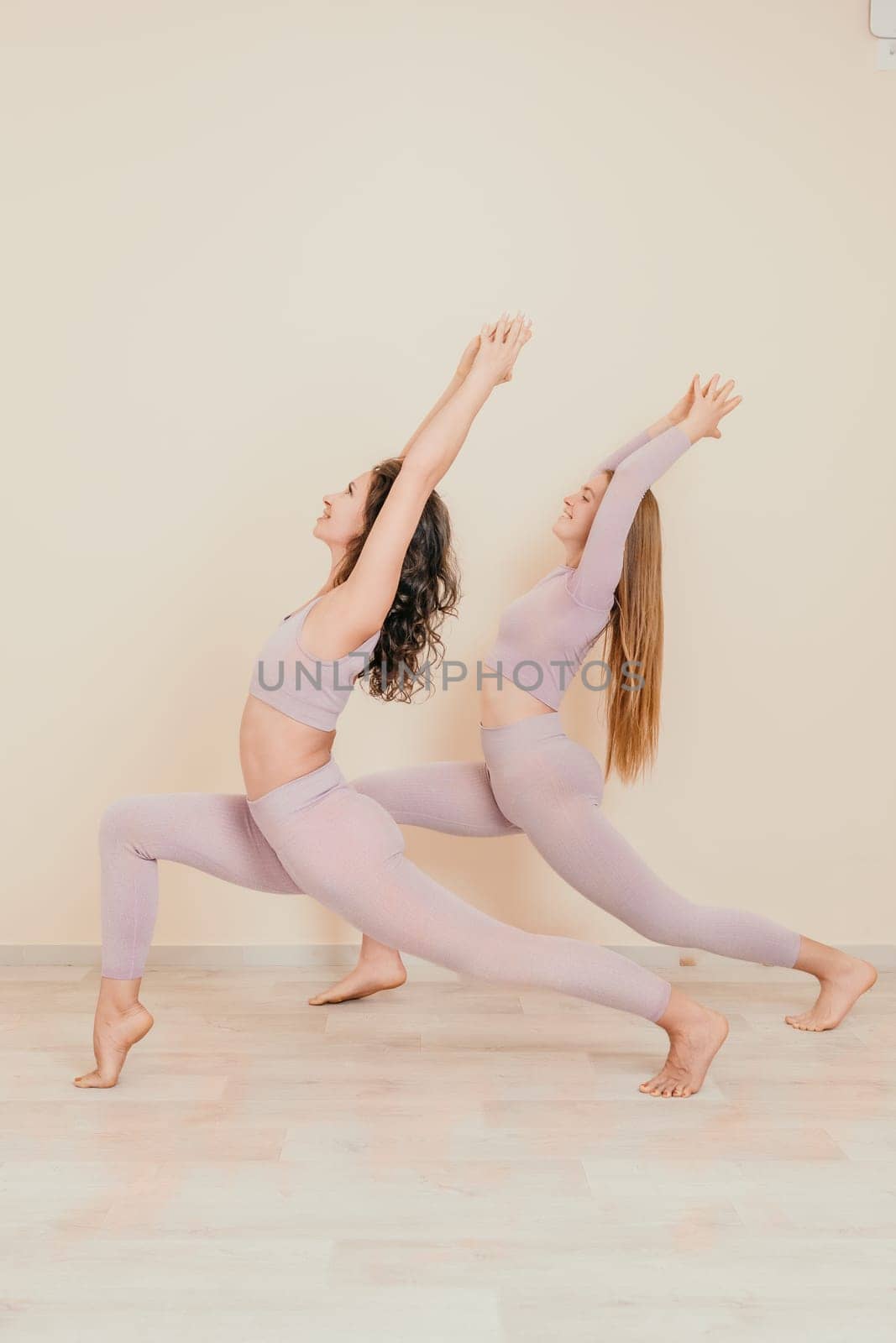 Young woman with long hair in white swimsuit and boho style braclets practicing outdoors on yoga mat by the sea on a sunset. Women's yoga fitness routine. Healthy lifestyle, harmony and meditation