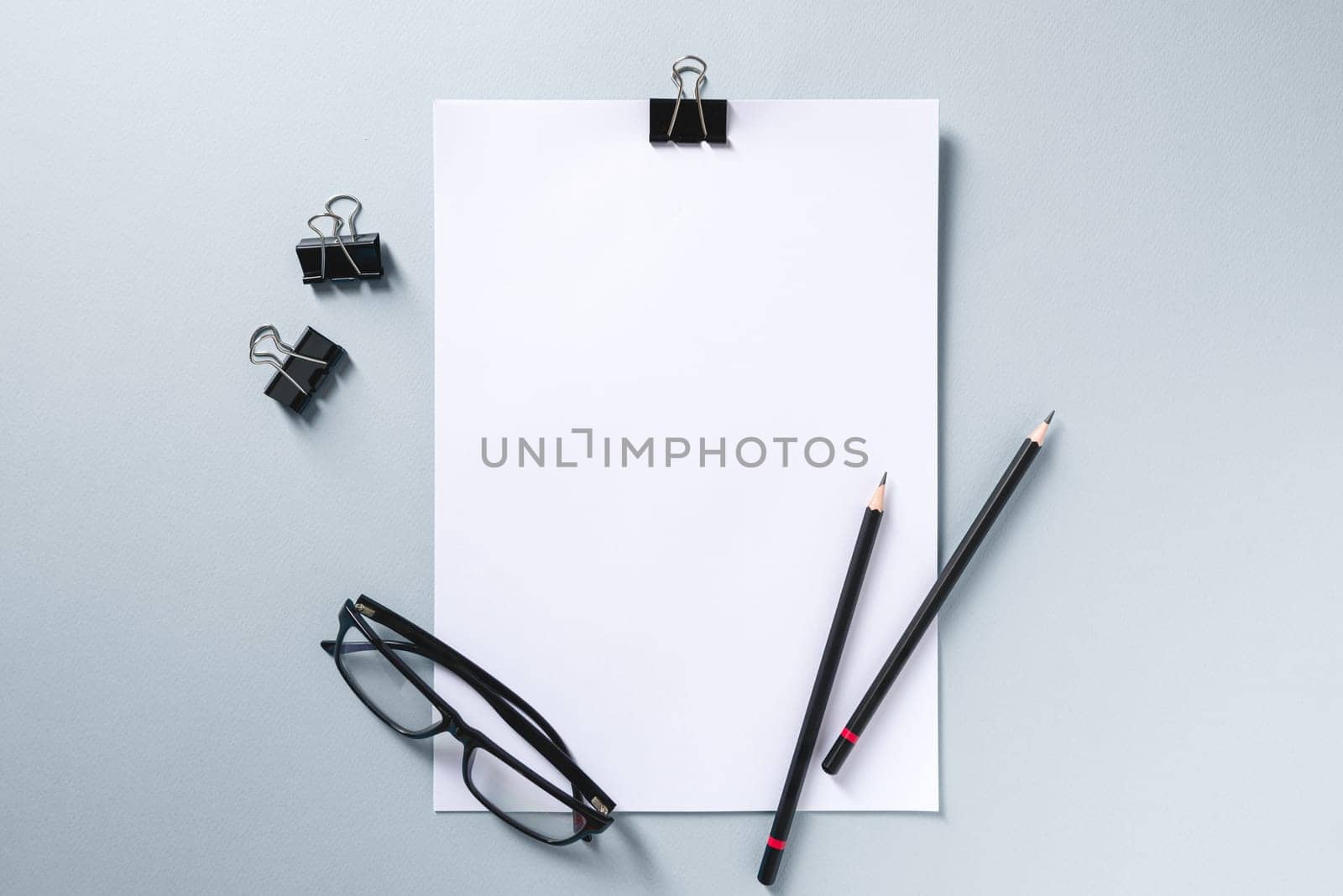 Top view of empty notebook, glasses and pen on grey office desk by Sonat