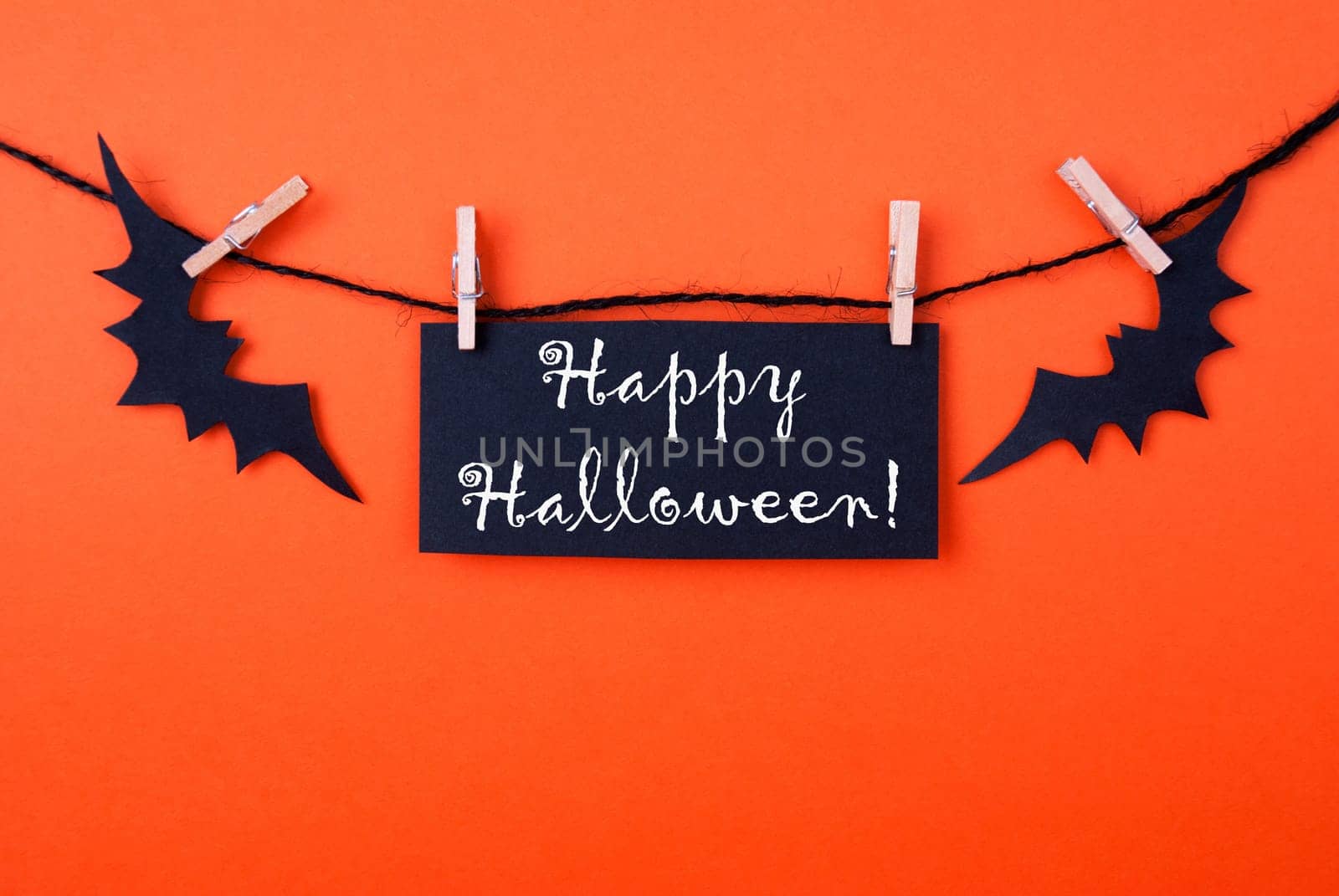 Orange Background with a Black Label and two Bats on a Line with Happy Halloween on it
