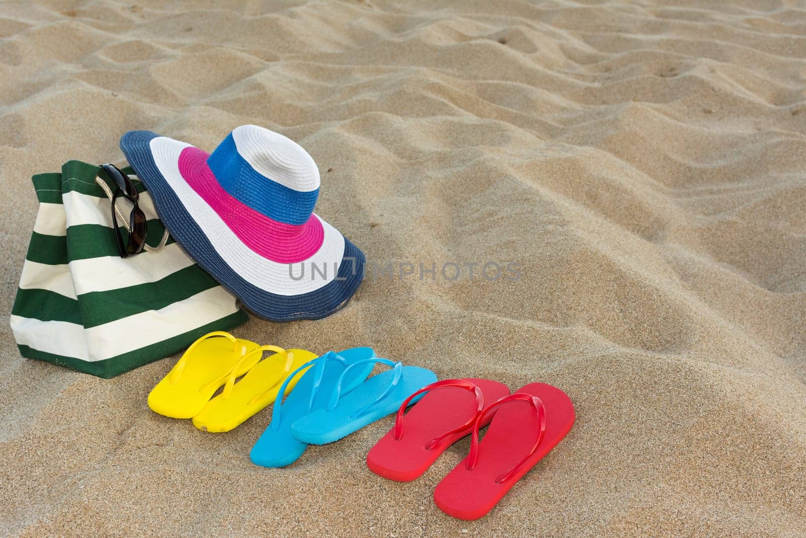 Summer concept of straw hat, bag, sunglasses and flip flops on a tropical beach.