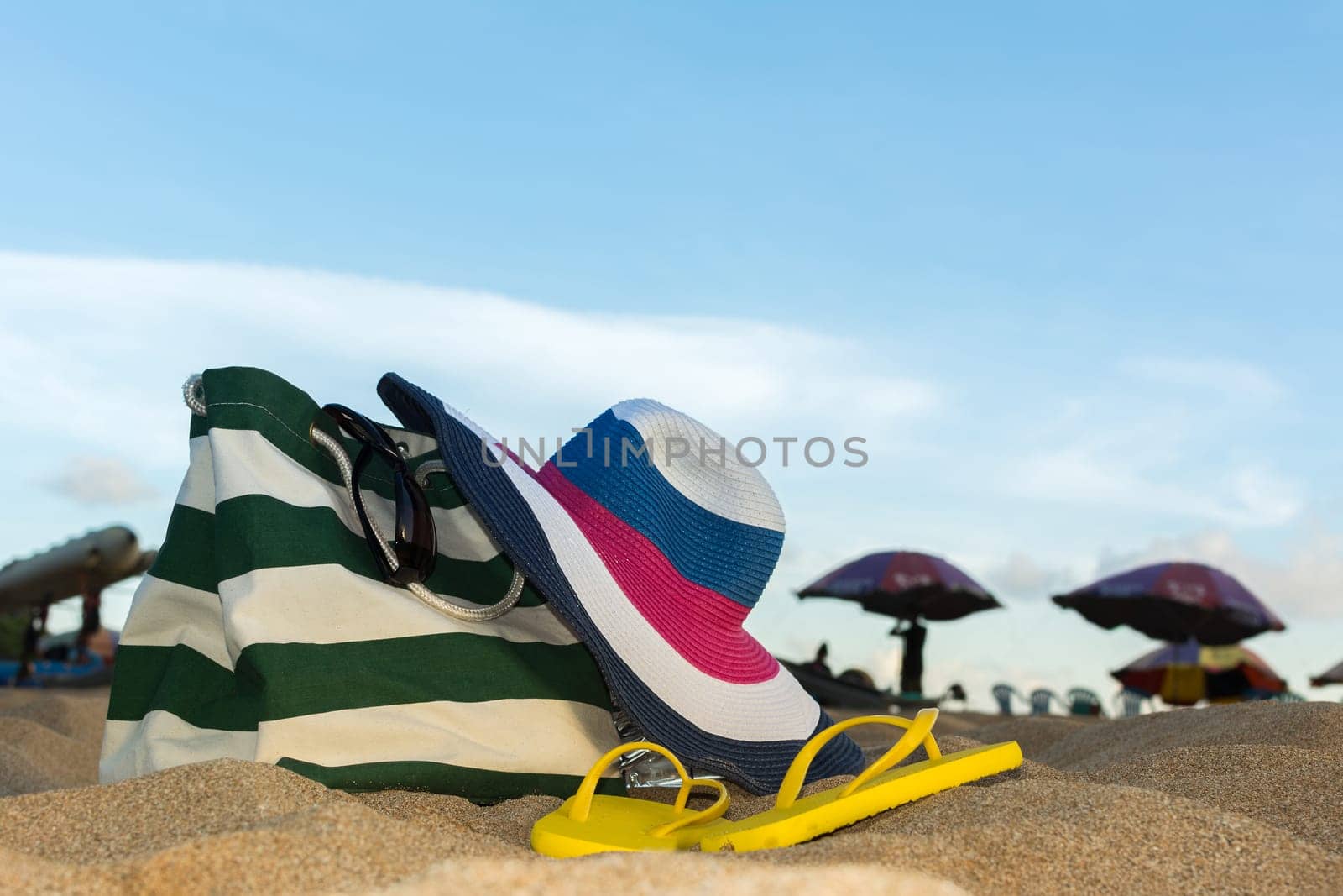 Summer concept of straw hat, bag, sunglasses and flip flops on a tropical beach.
