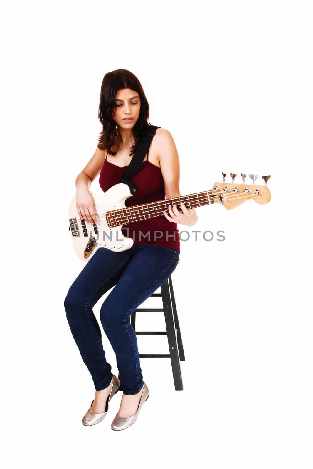 A young woman sitting on a chair, playing her guitar, isolated on white.background..