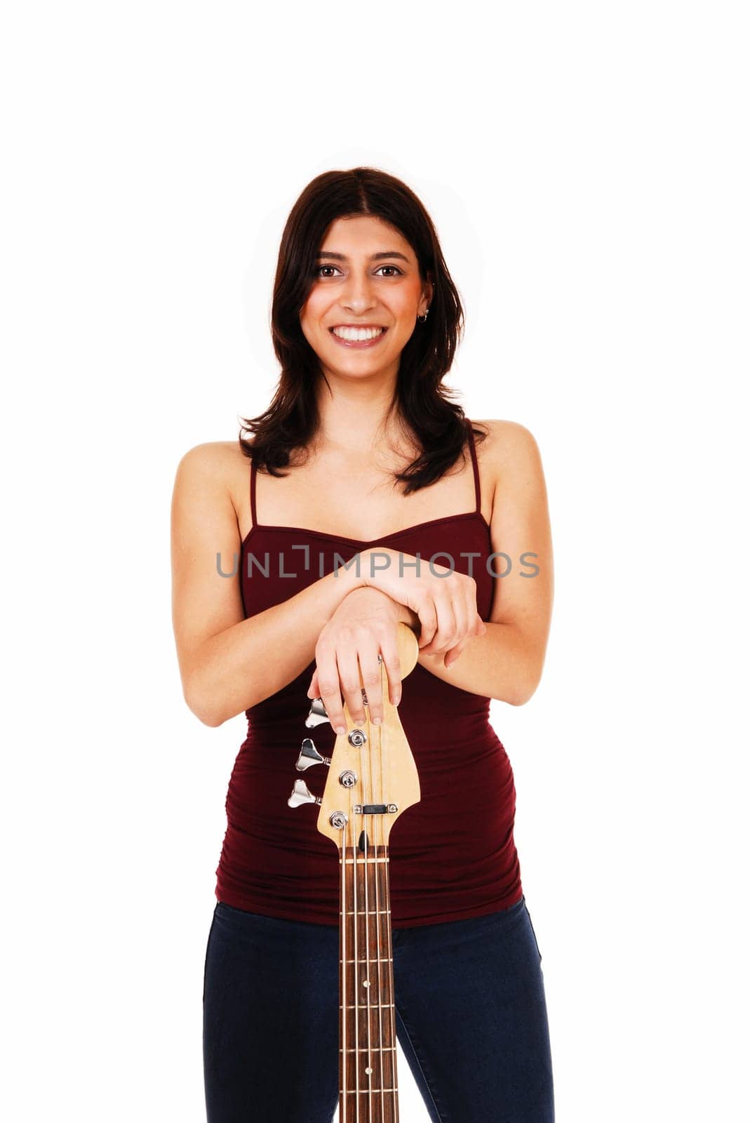 A lovely young woman standing in jeans, isolated on white background,.holding her guitar and smiling..