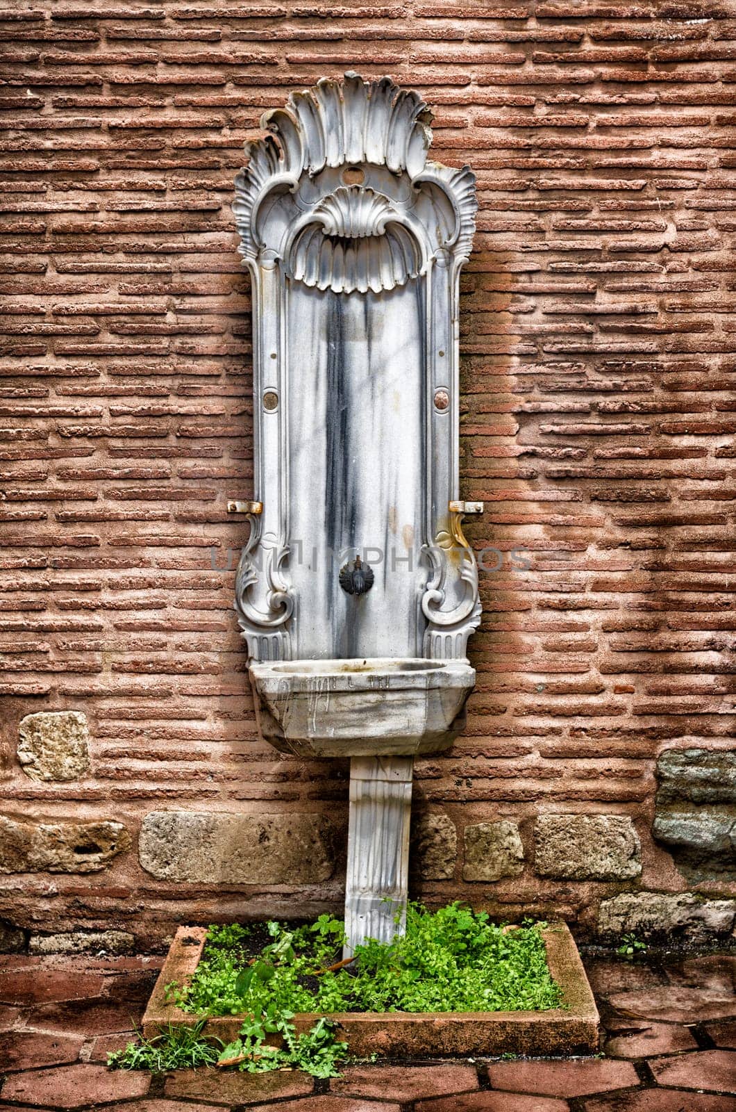 vintage marble fountain against a brick wall