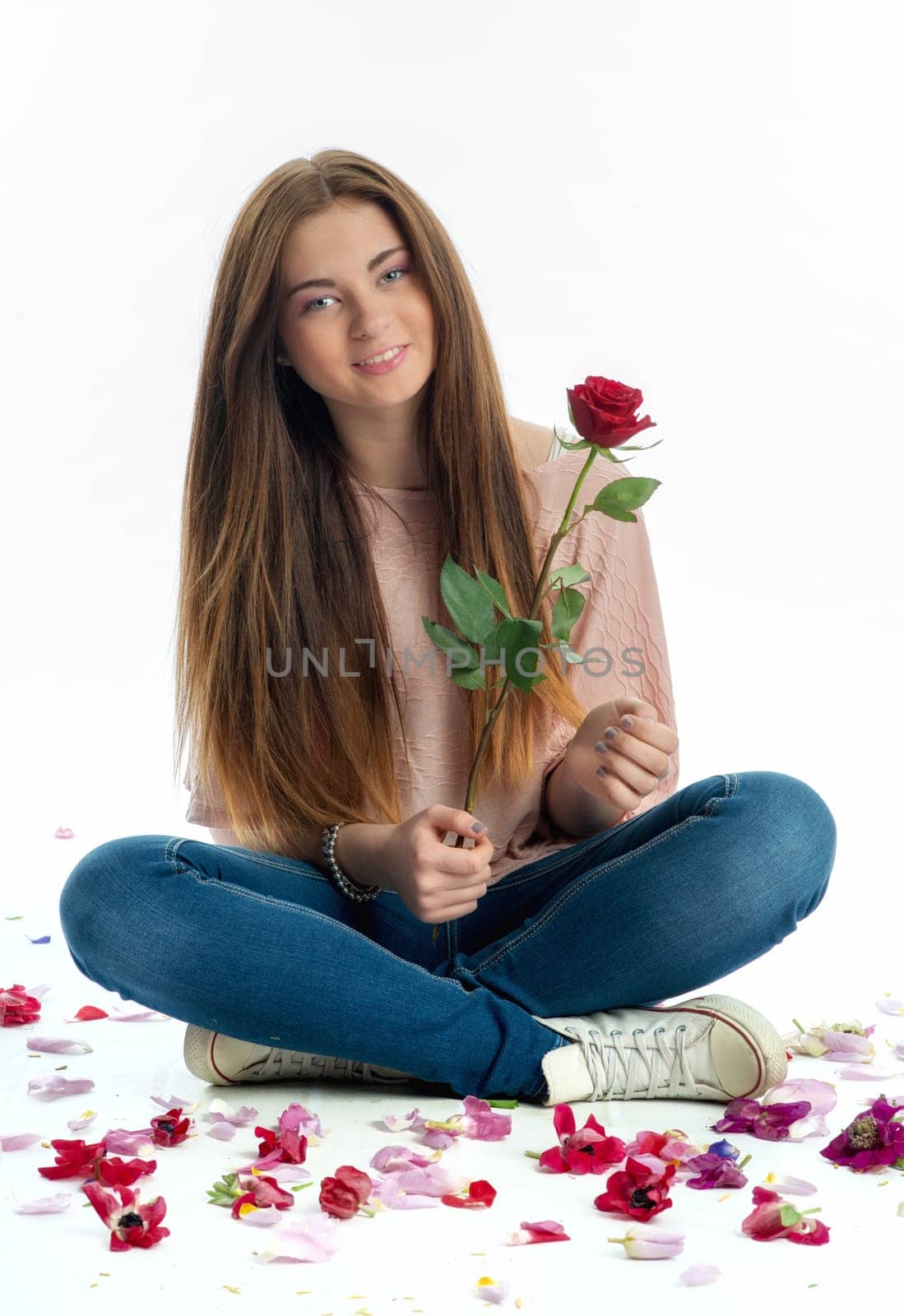 Girl sits amid rose petals