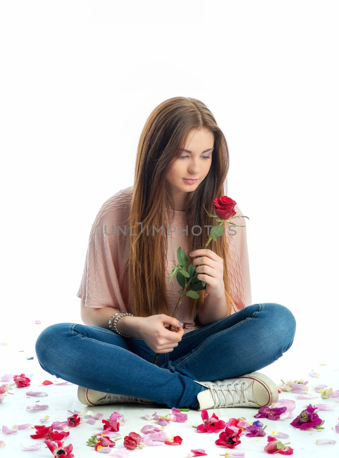 Girl sits amid rose petals