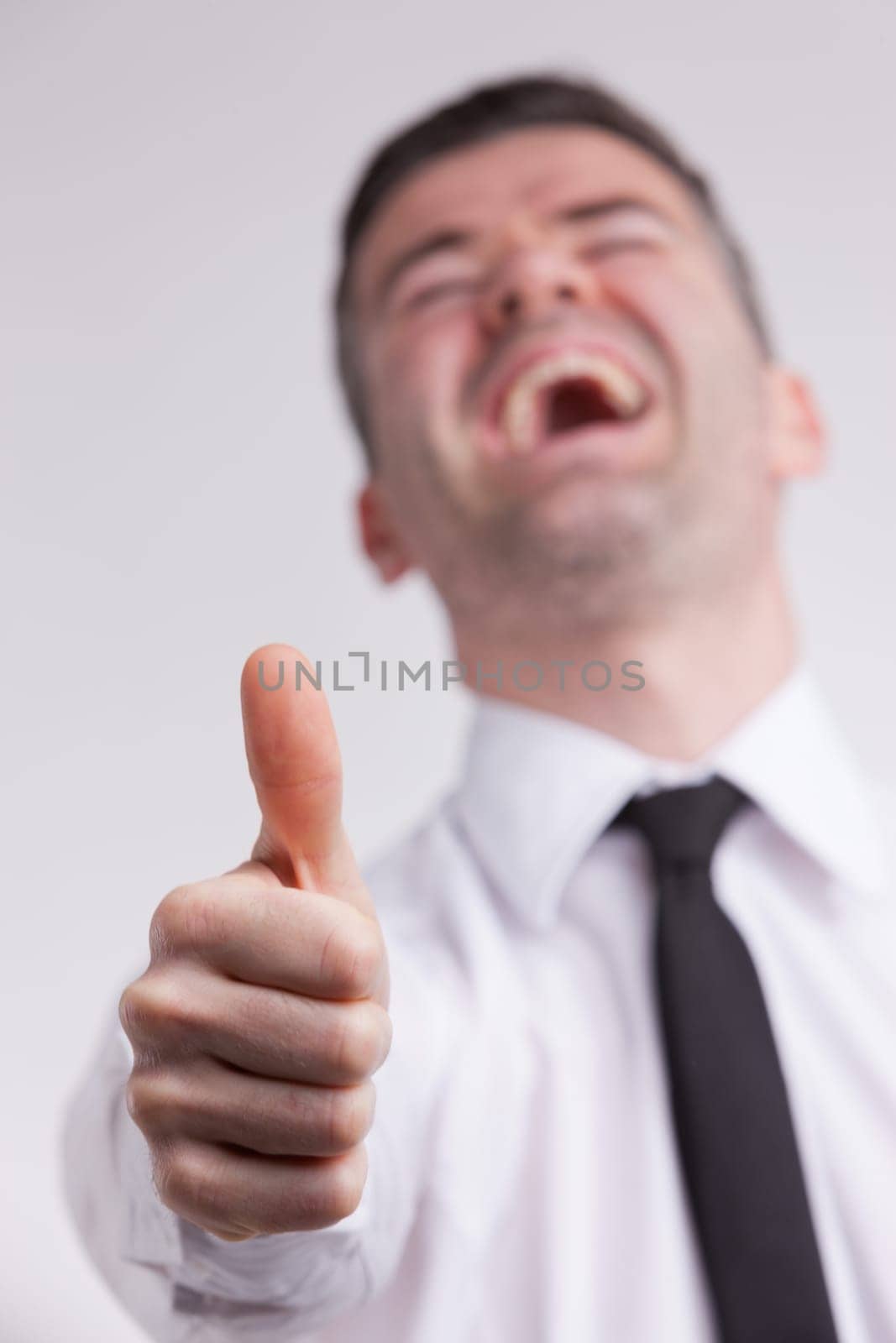 this man shows a thumbs up sign while he smiles cheerful because he probably strongs agrees or likes what's going on