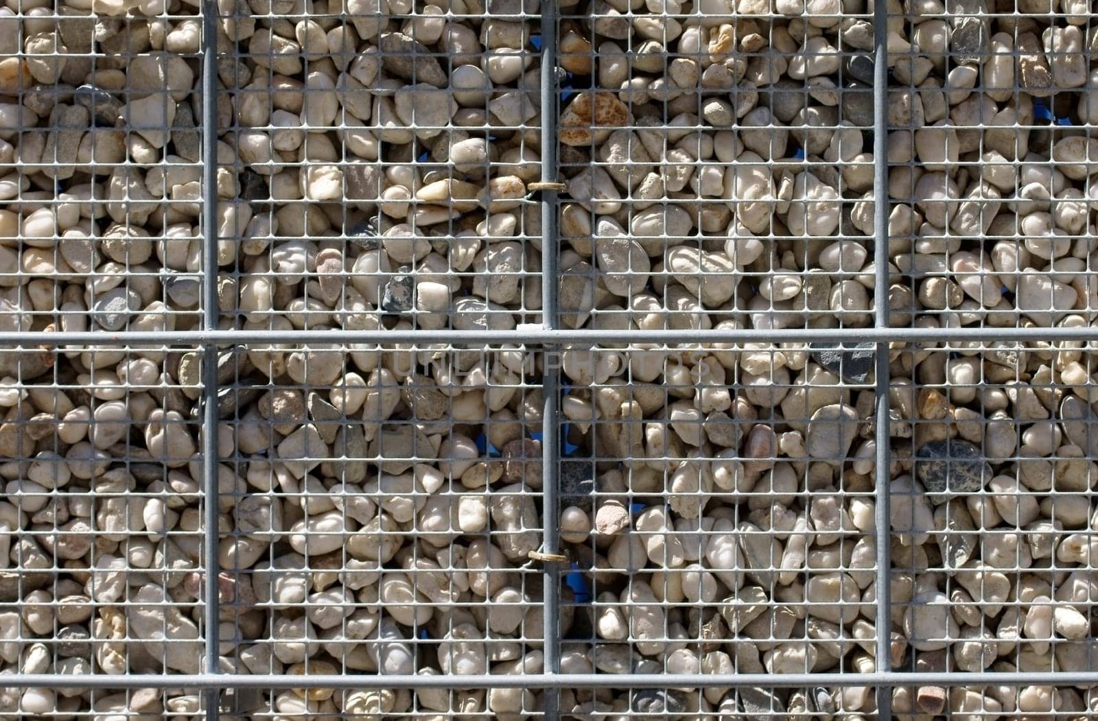 The photograph of a steel grid with pebbles usable as a fence.