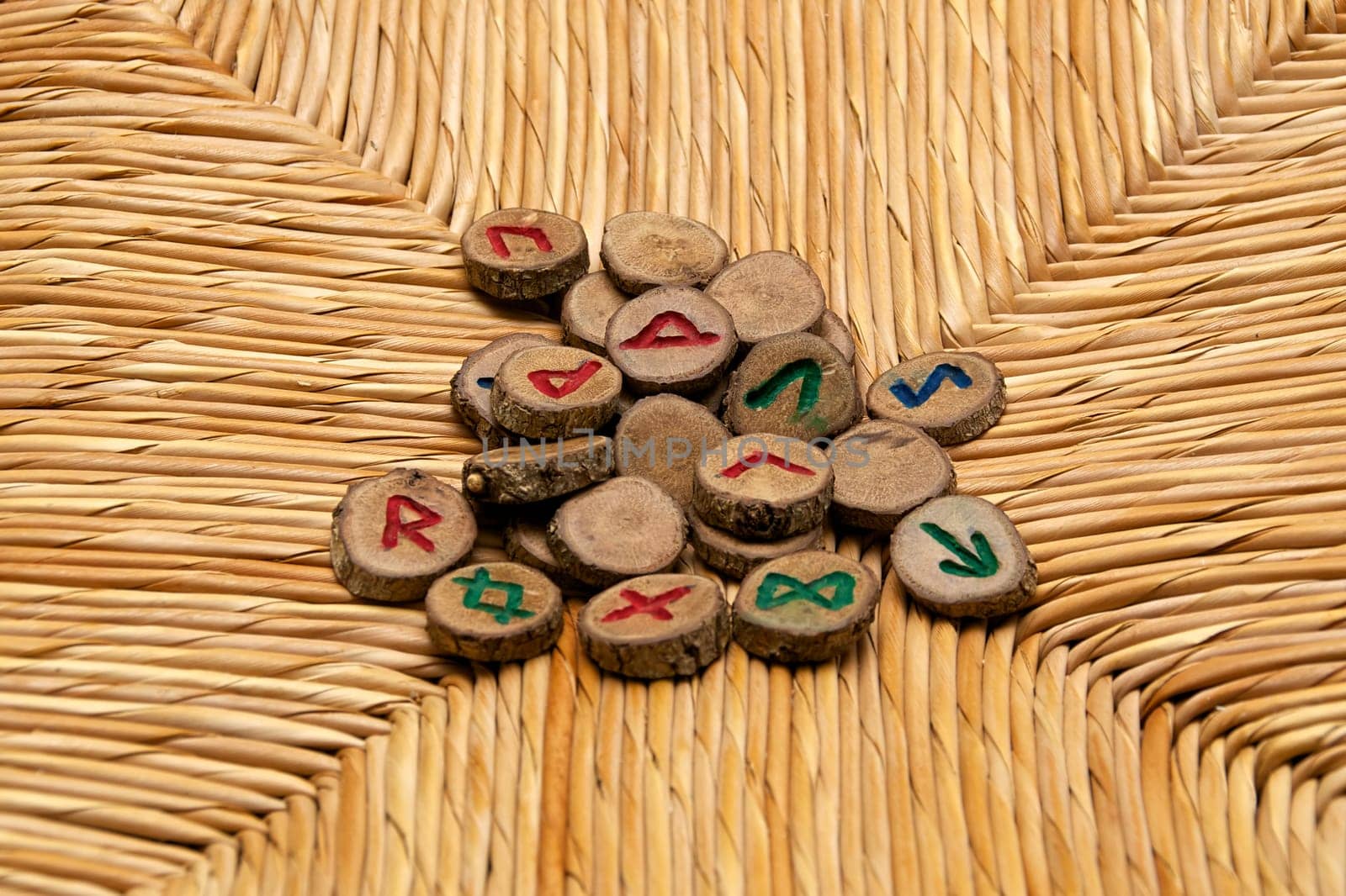 A pile of germanic runes, an ancient alphabet known as the futhark are on a woven rattan surface..Note