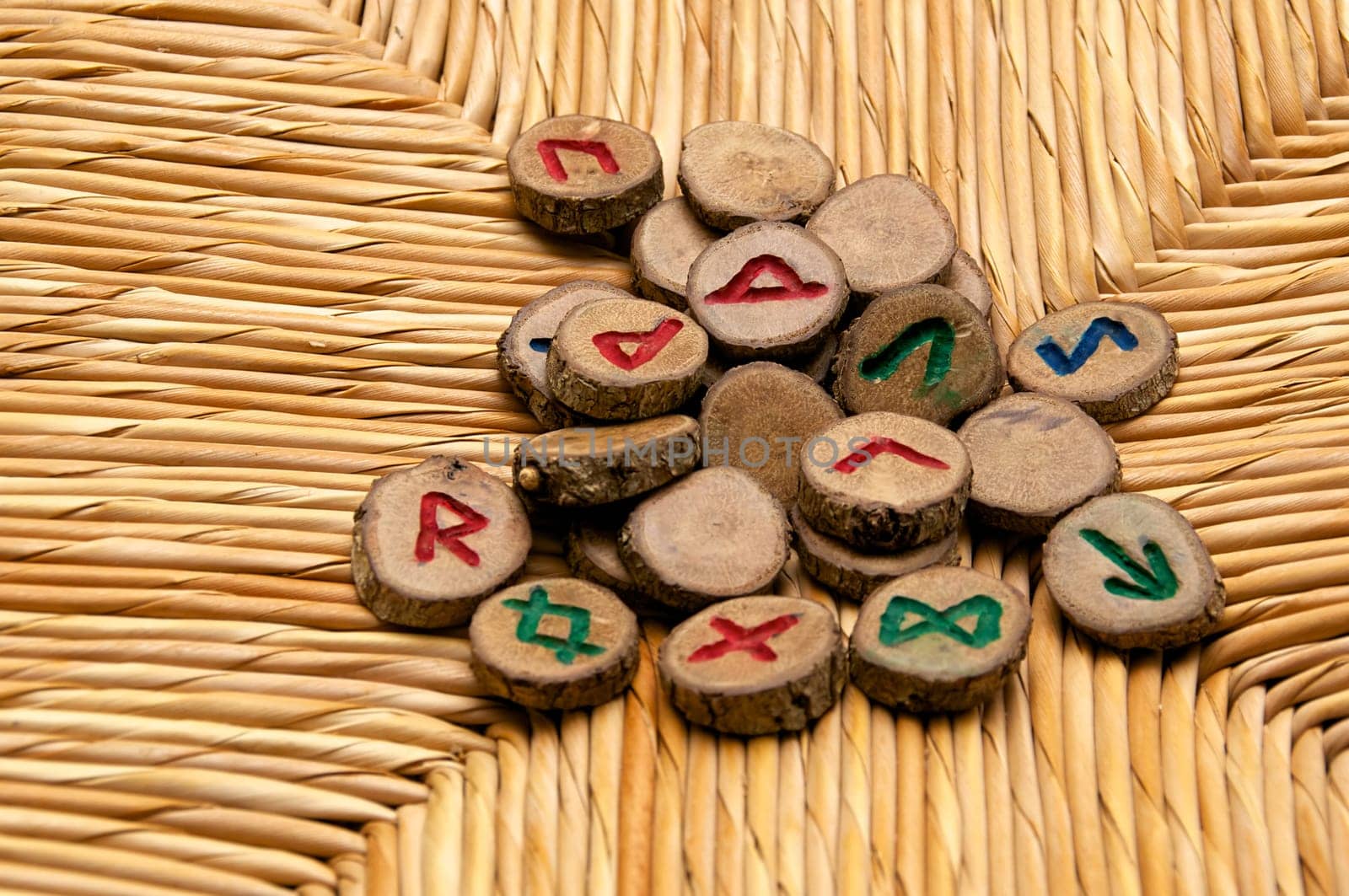 A pile of germanic runes, an ancient alphabet known as the futhark are on a woven rattan surface..Note