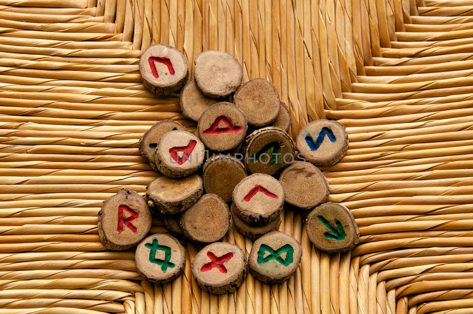 Looking own on a pile of germanic runes, an ancient alphabet known as the futhark on a woven rattan surface..Note