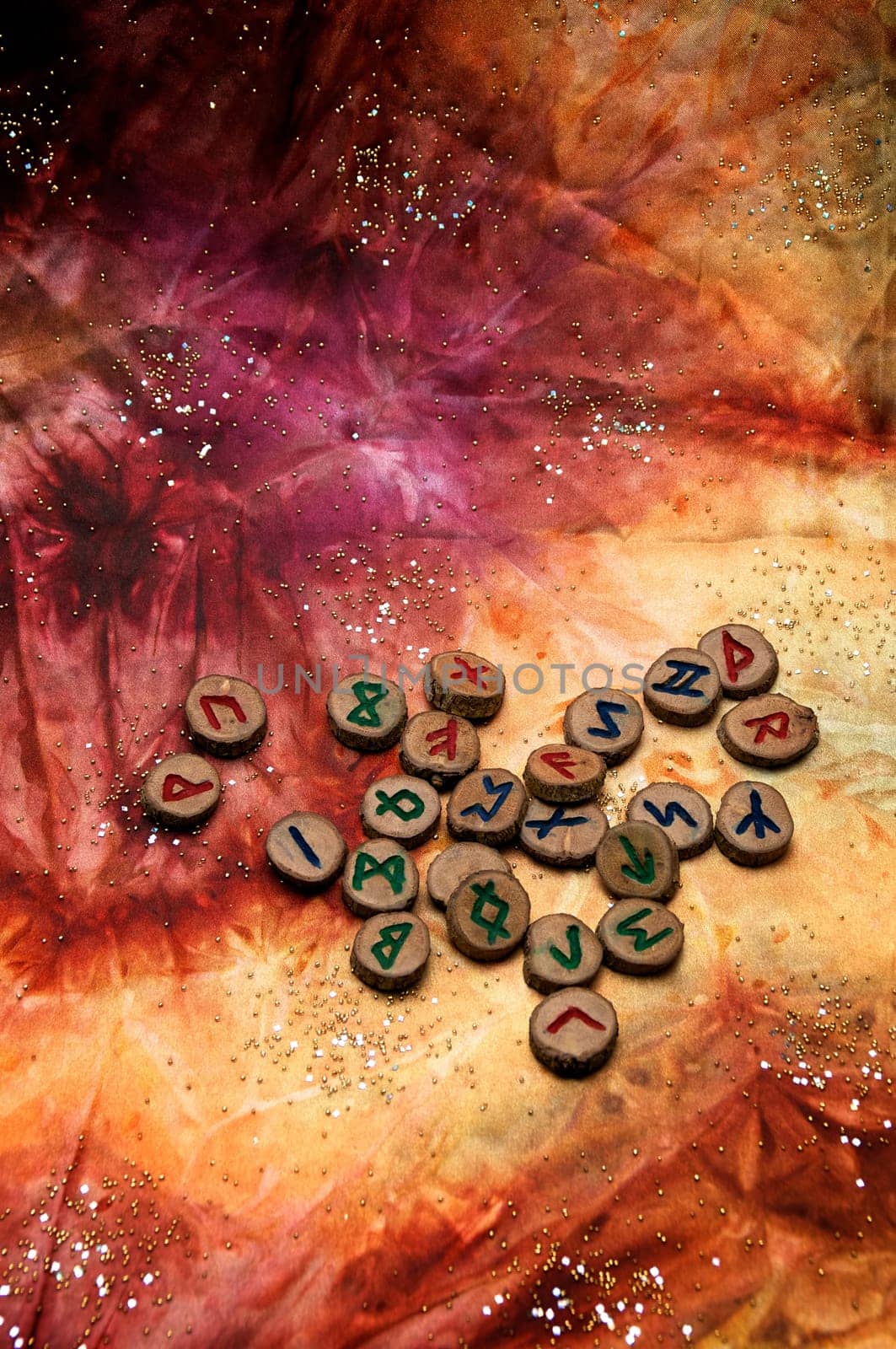 hand carved and painted wooden runes, an ancient alphabet known as the futhark are on a colorful hand dyed fabric with small sparkling beads..Note