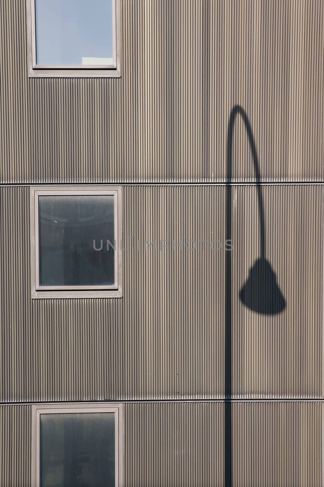 The photograph of a facade with windows and the shadow of a lantern.