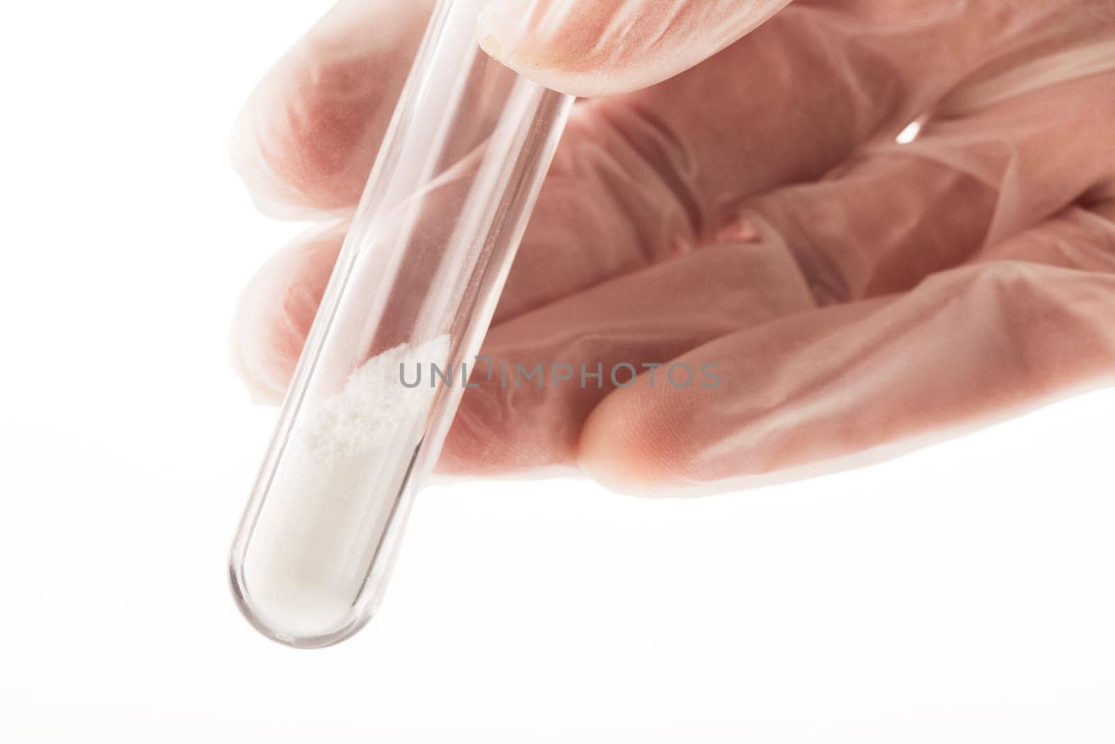White powder in test tube held by fingers in latex gloves.