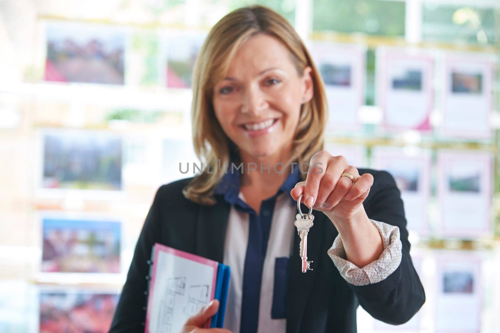 Estate Agent In Office Holding Keys To Property