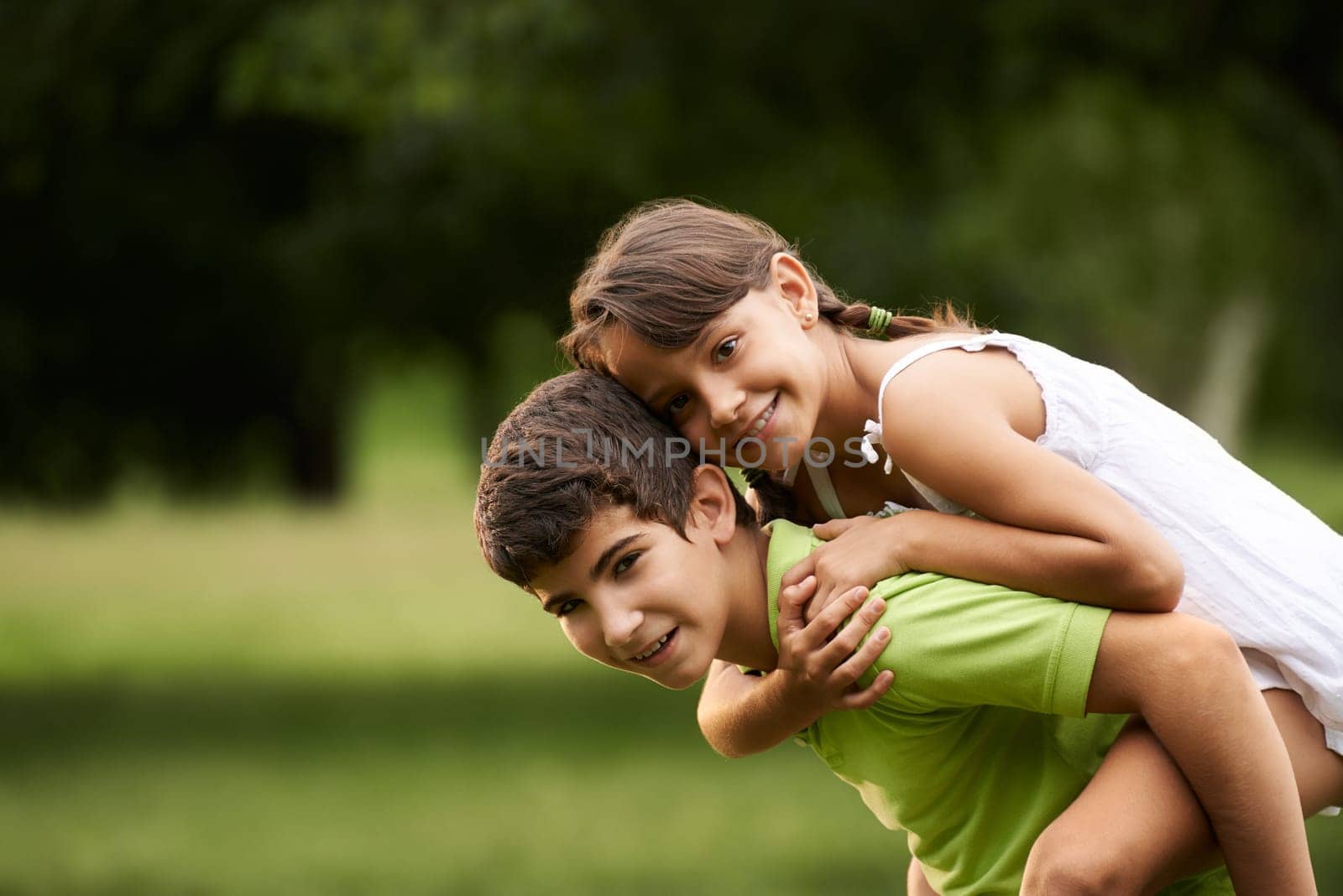 People in love with happy little girl and boy running piggyback in city park. Copy space