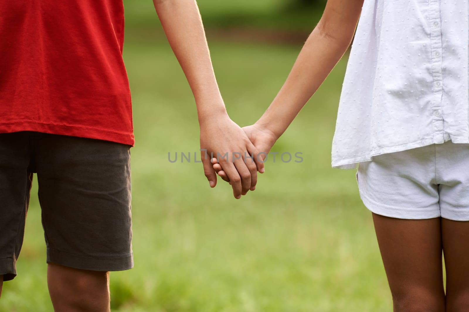 People in love with little girl and boy holding hands in park. Cropped view