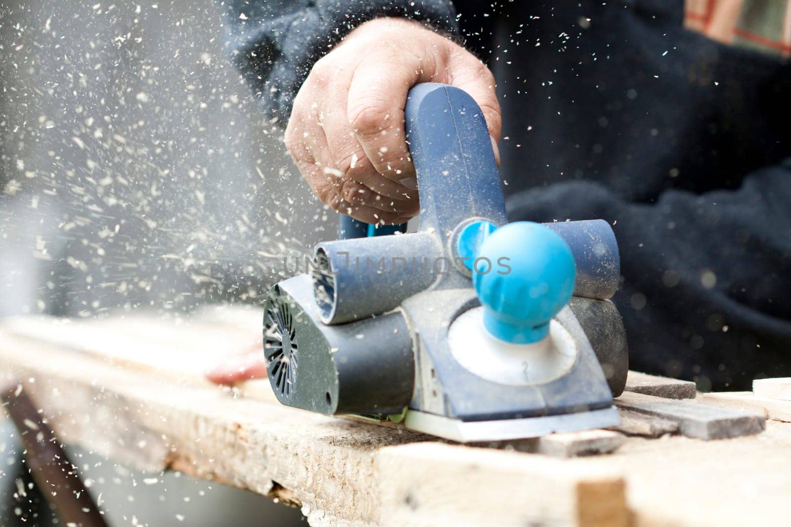 Worker's arm sawing wood board in the workshop