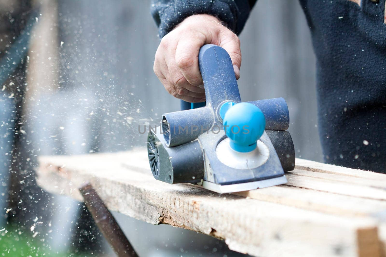 Worker's arm sawing wood board in the workshop