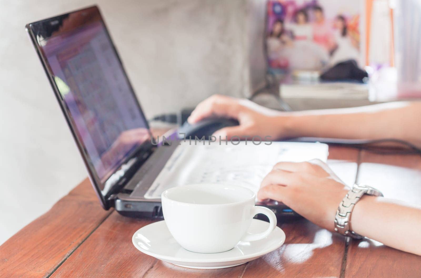 Woman using laptop with a cup of coffee, stock photo